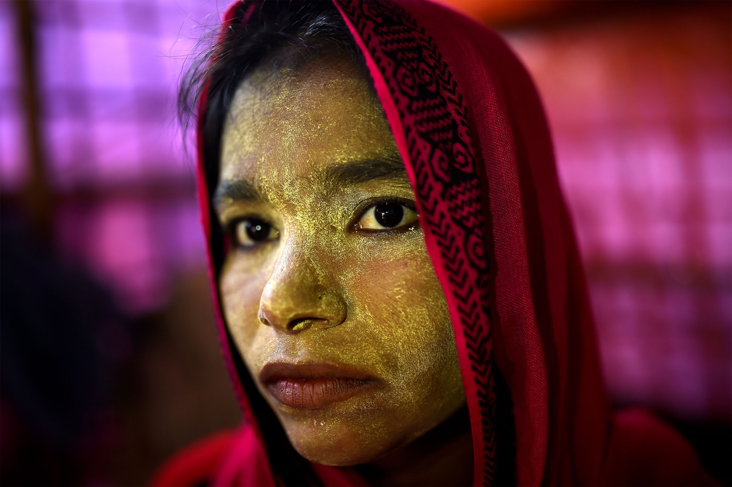 a Rohingya girl wearing paint on her face to protect her from the sun