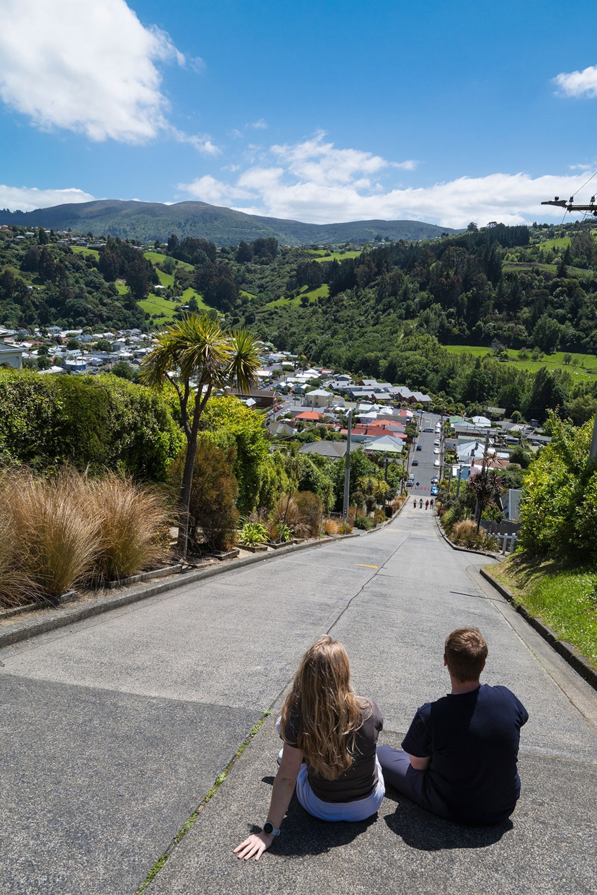 Two people sit at the top of Baldwin Street, the world's steepest street, in Dunedin, New Zealand