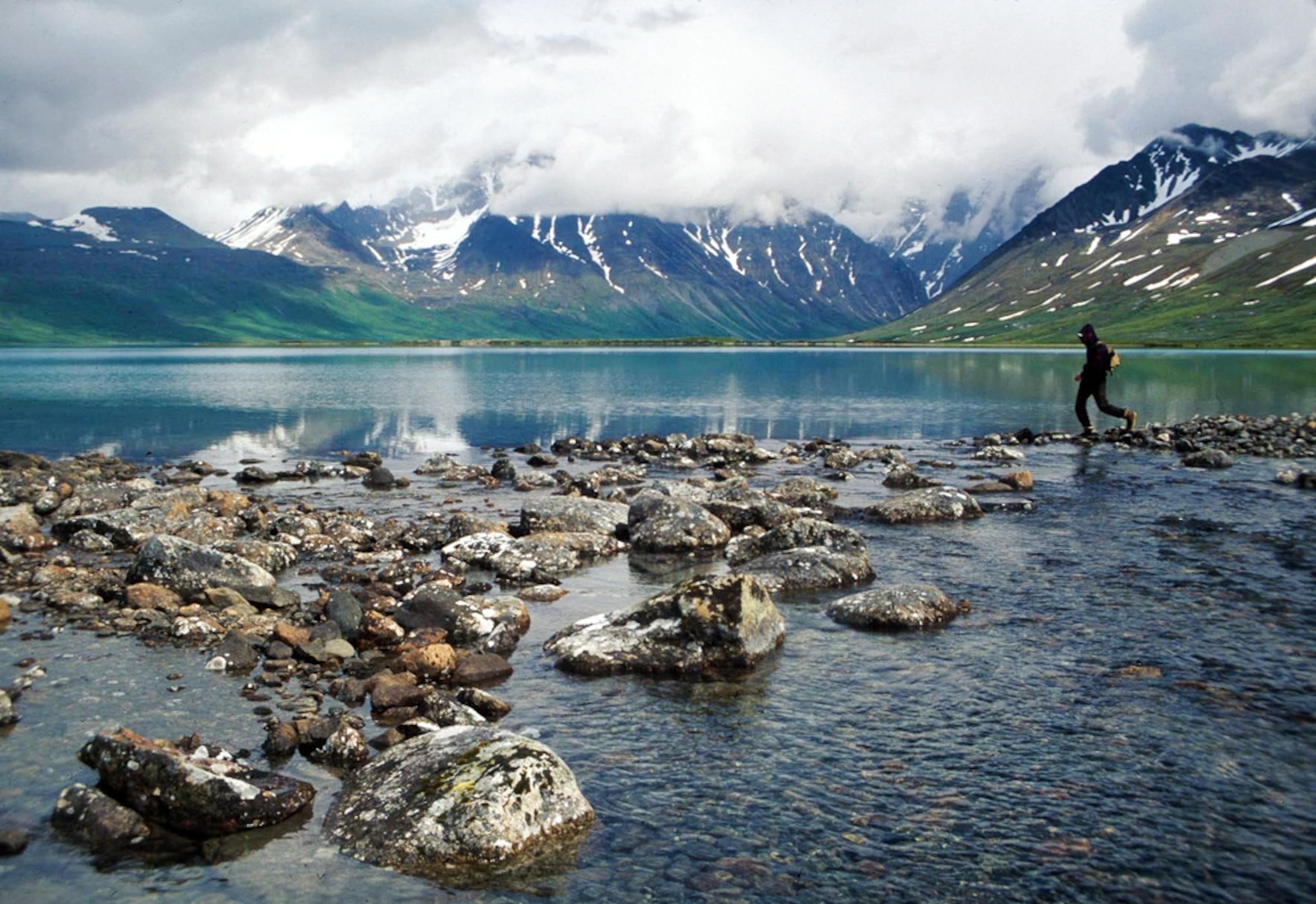 A visitor on the rocks in Mulchatna River at Turquoise Lake in Lake Clark National Park, Alaska.