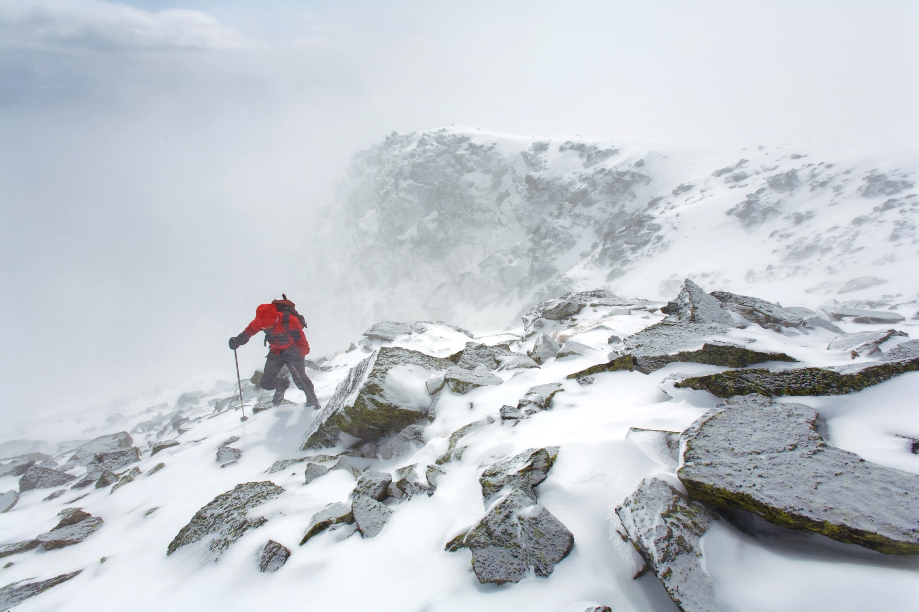a hiker scraping through Arctic-like conditions on the lip of Huntington Ravine