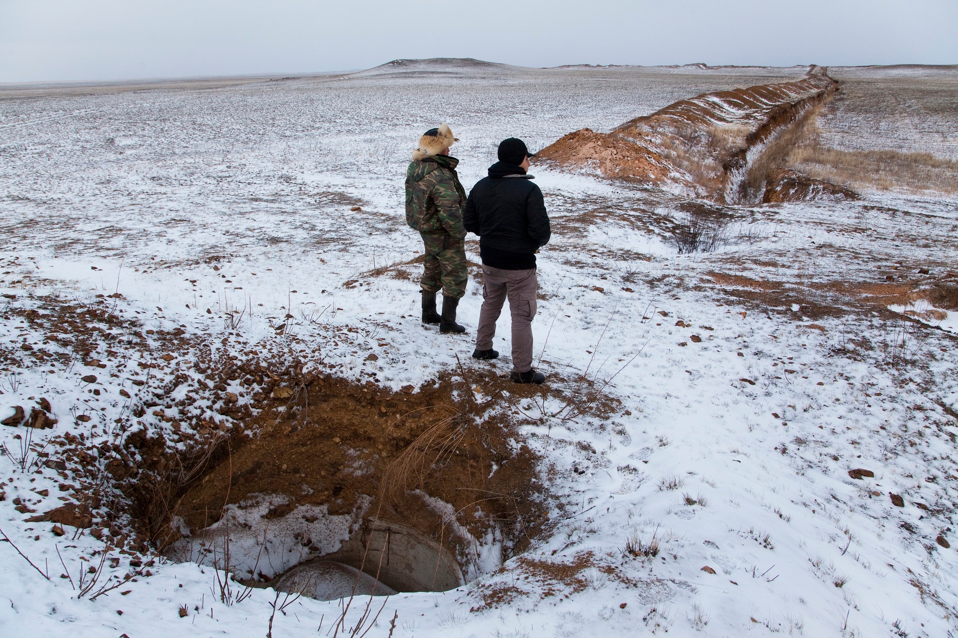 Rahimzhanov Zhumabai and a friend look down a ravine where a pipeline was dug up. Photograph by Ryan Bell