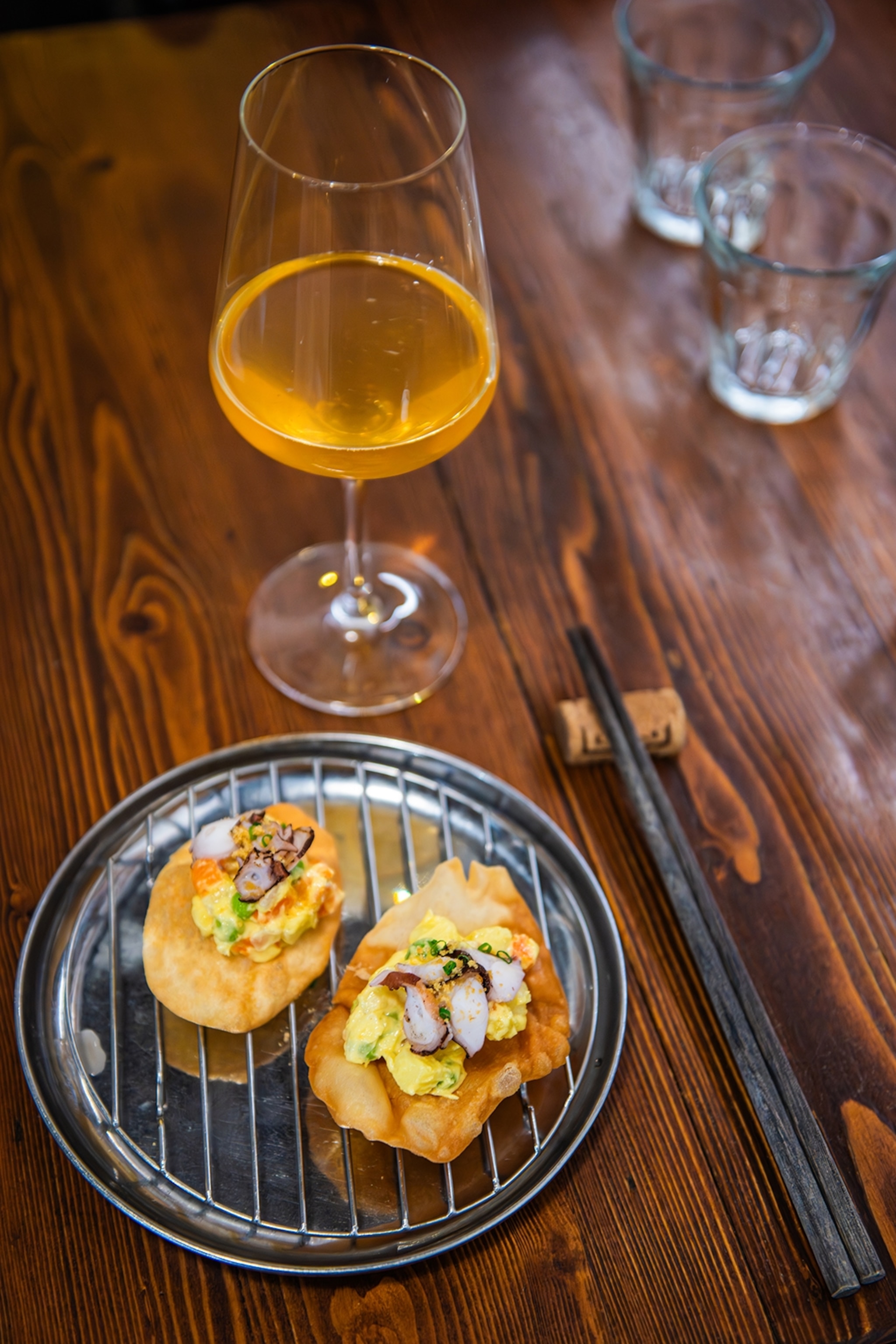 A close-up on two toasties served with orange wine and chopsticks.