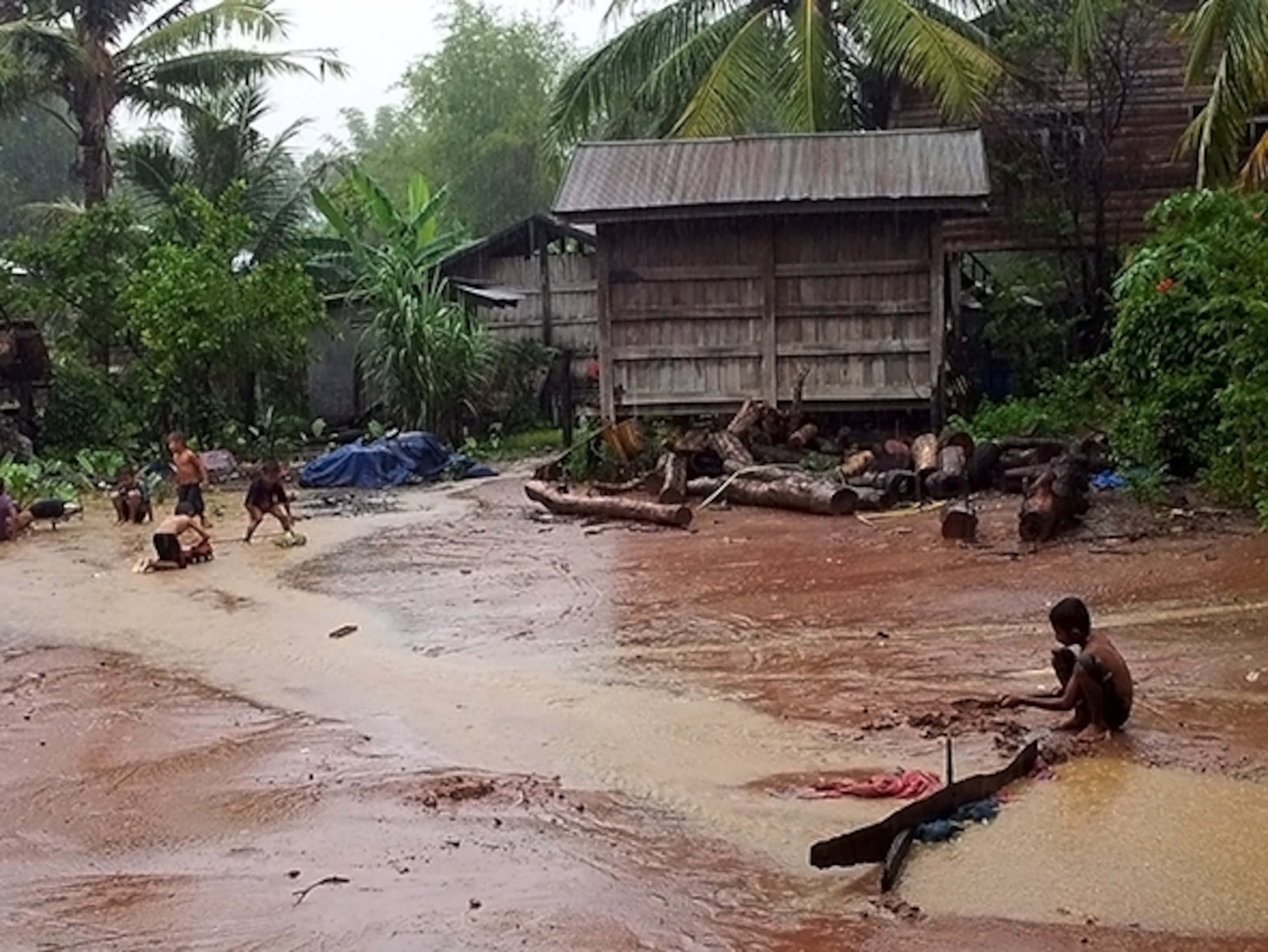 Village children help to build a dam following a driving rain. (Photograph by Don George)