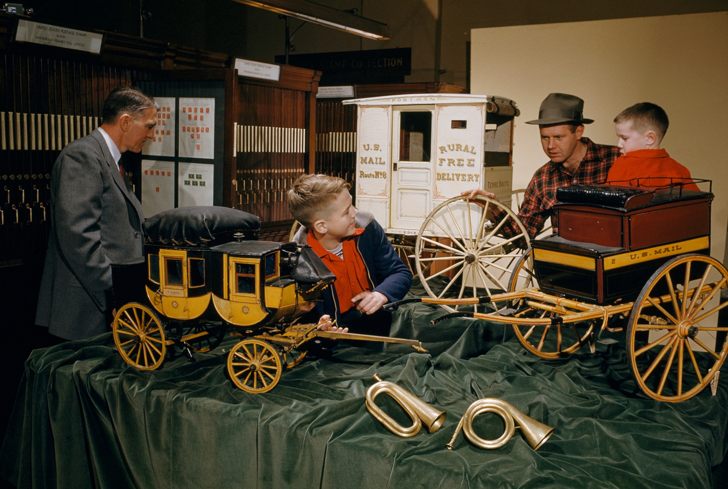 Boys and men inspect replicas of postal stage coaches.