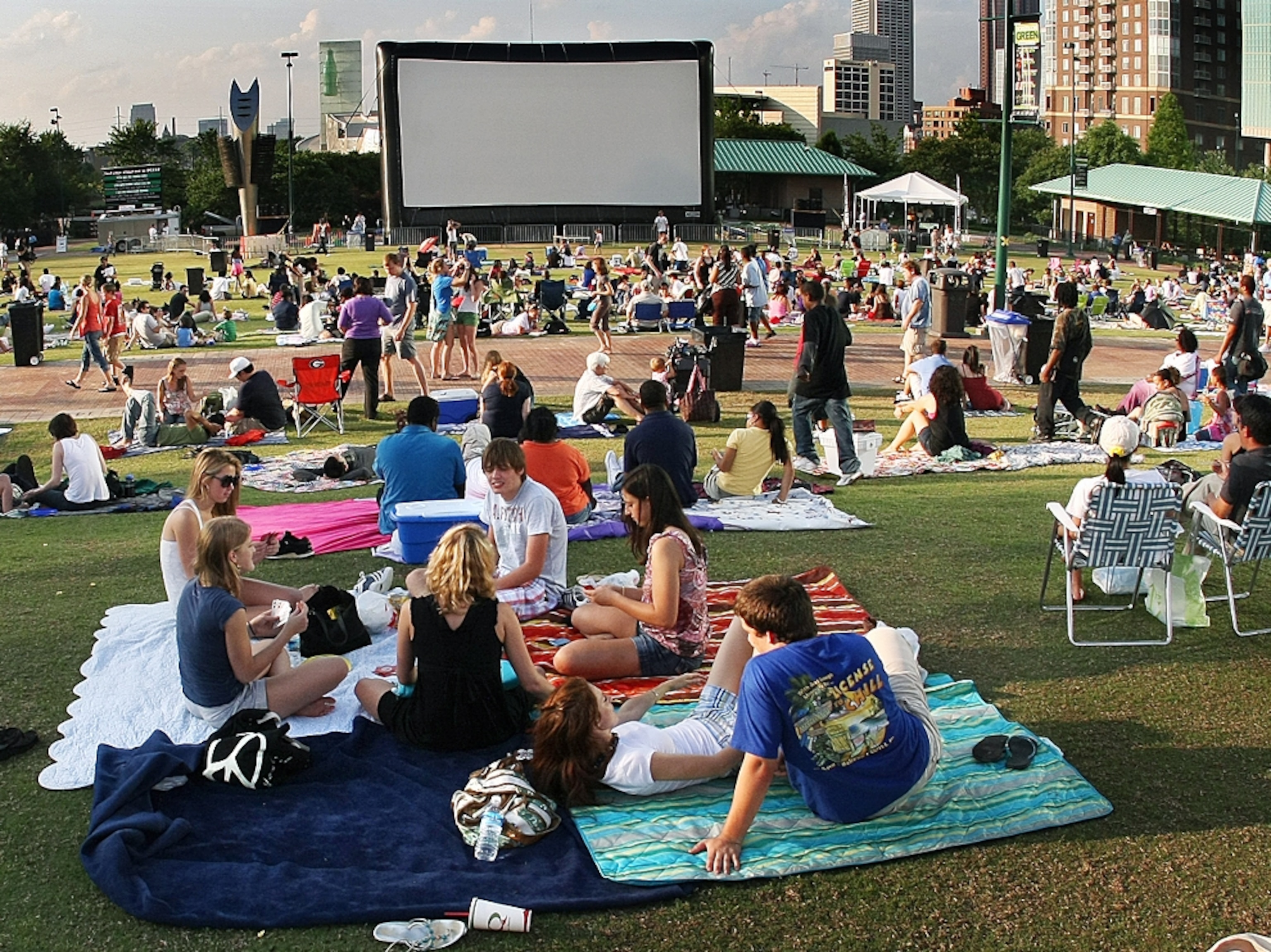 people setting up blankets to watch movie in a park