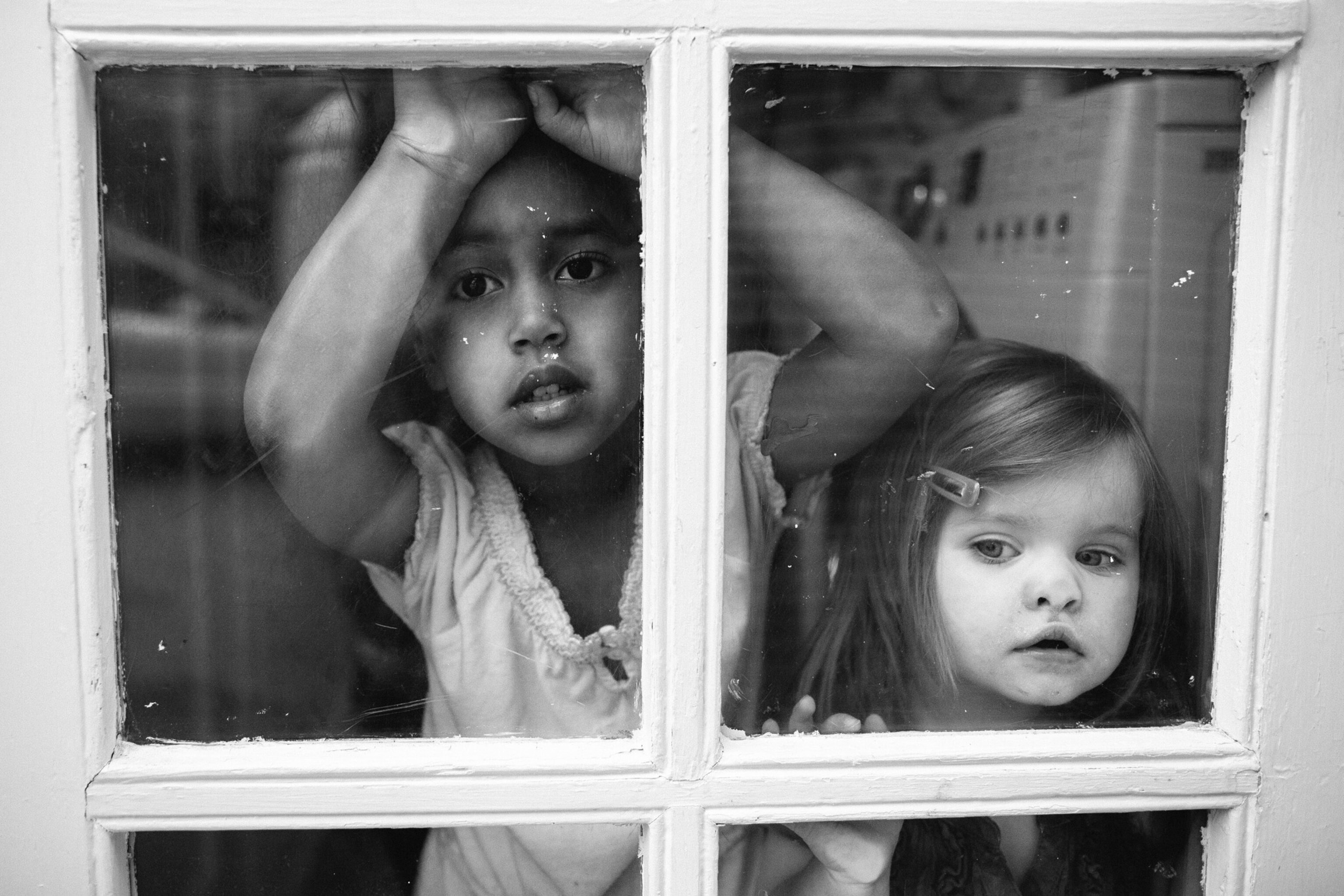 two young girls looking through a door