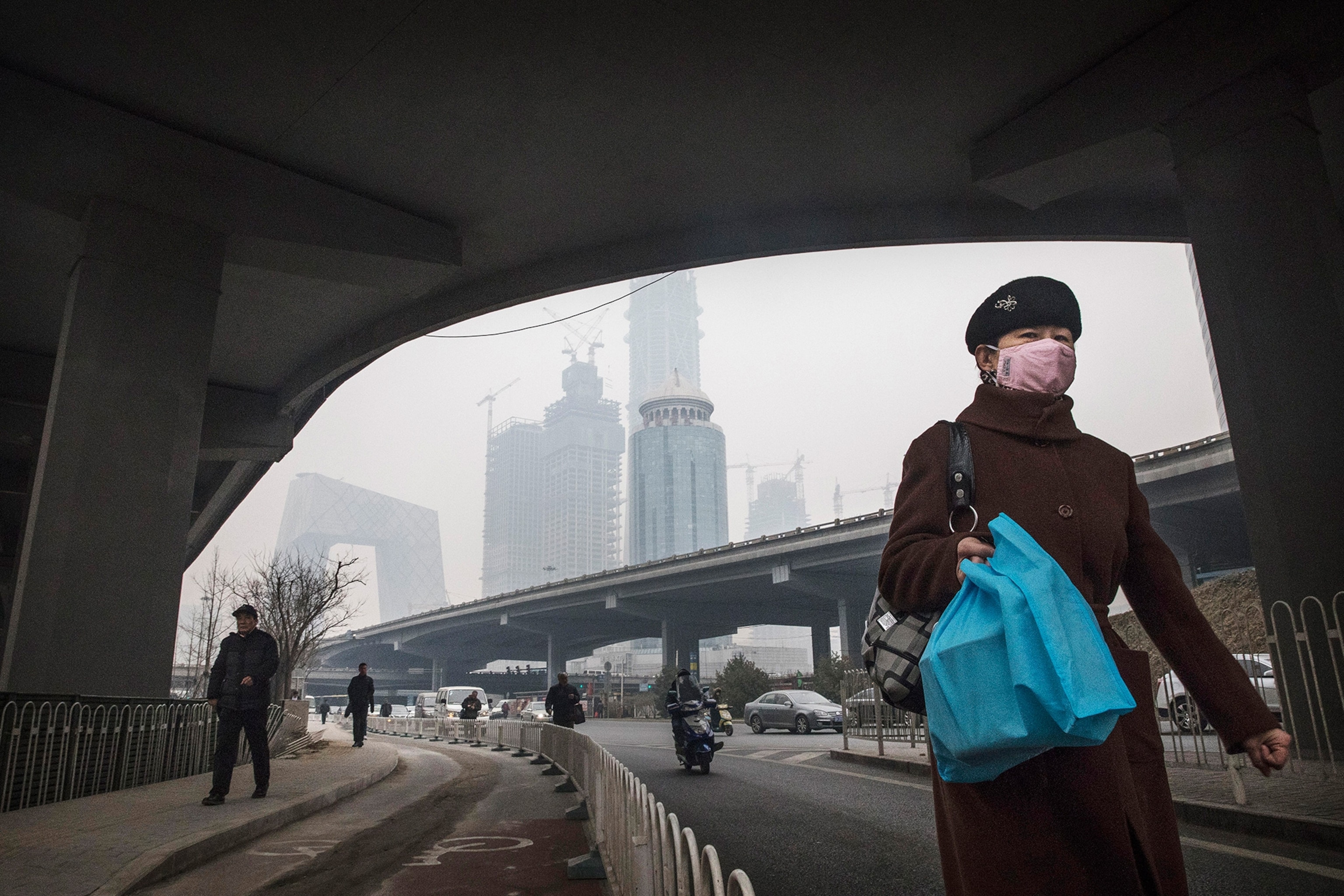 a Chinese woman wearing a mask as she walks in the street on a polluted day