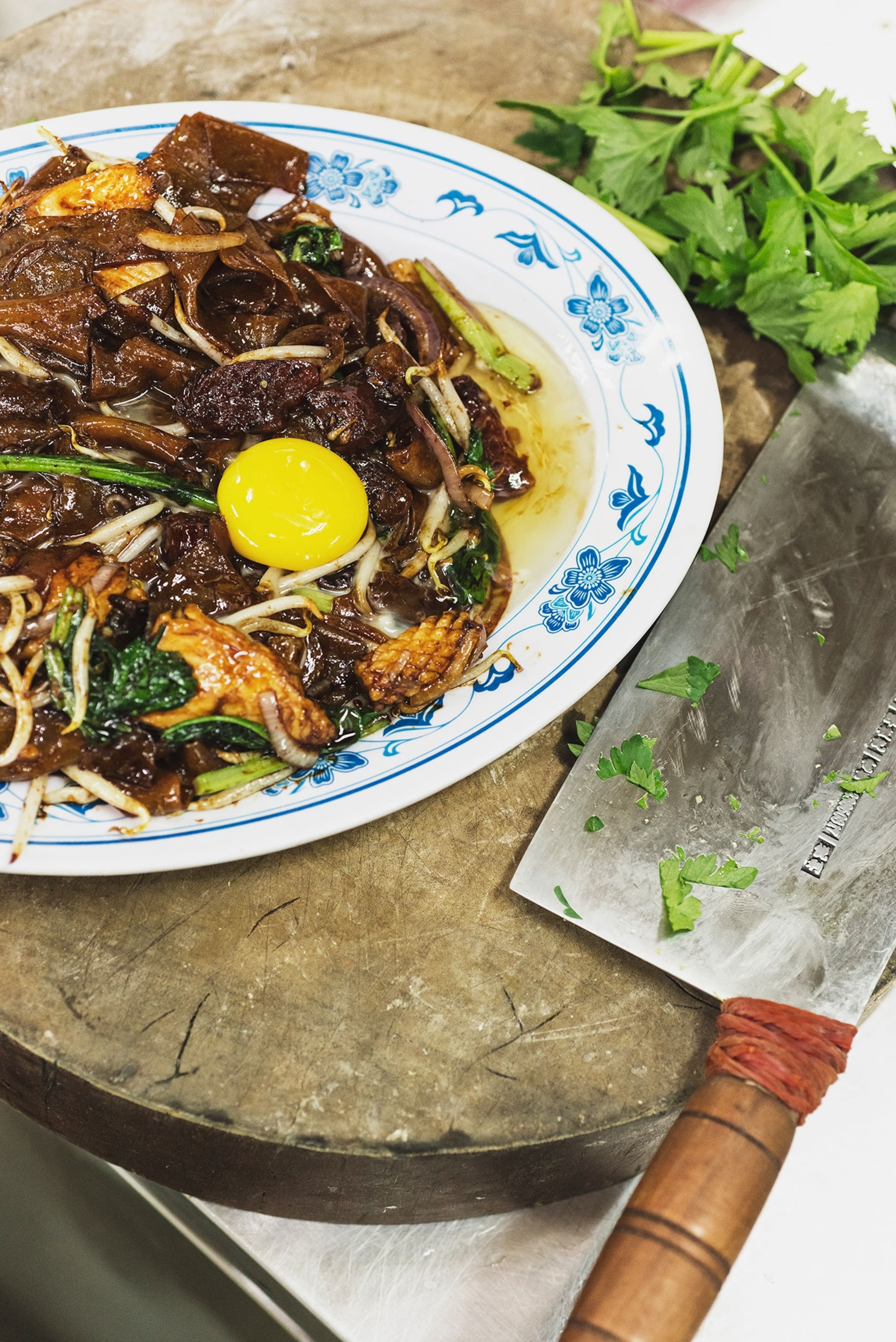 A bowl with a plate of broth sausage and noodles an egg sits on top.