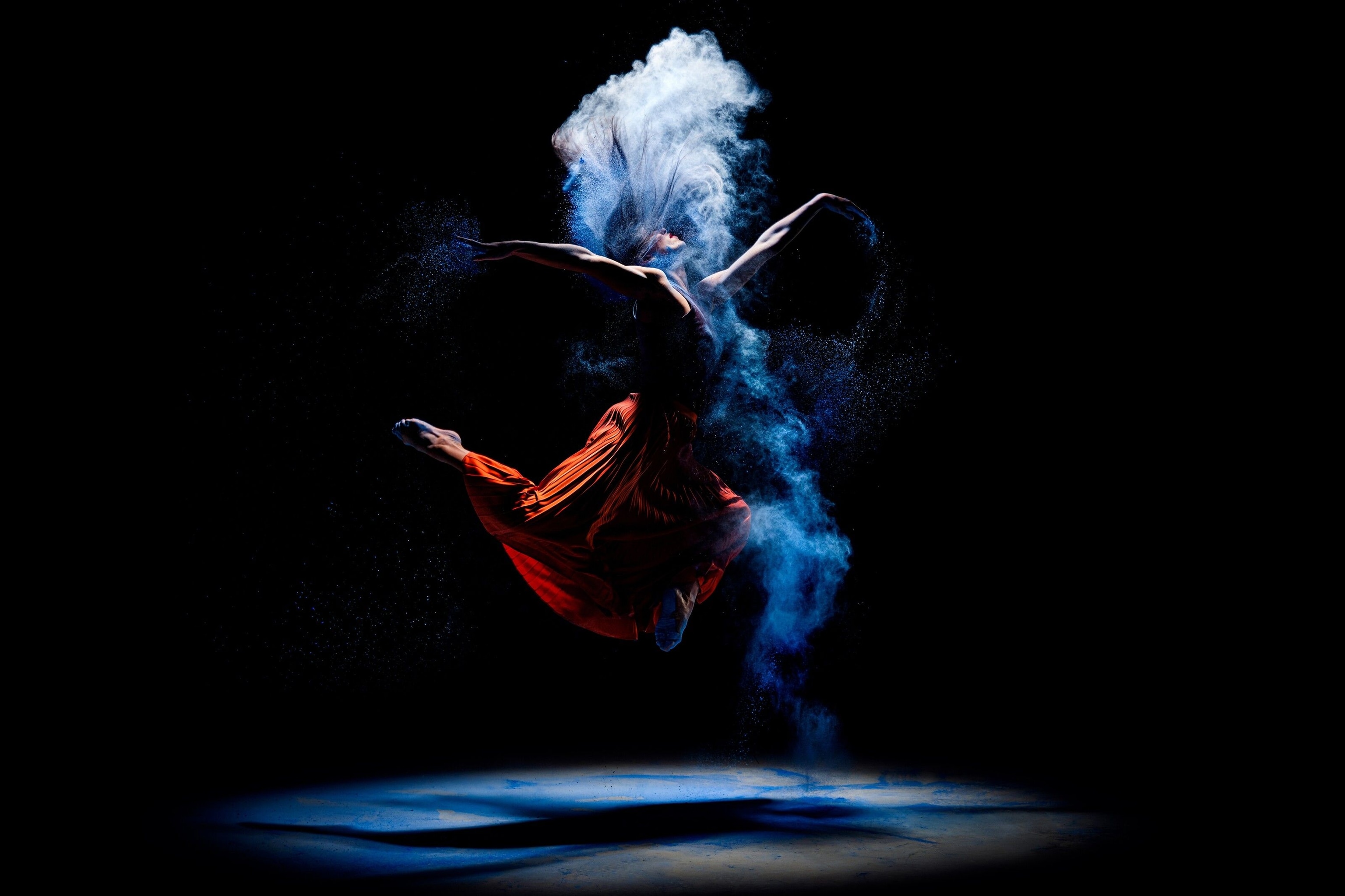A dancer in a cloud of smoke, illuminated only by a single spotlight from above.