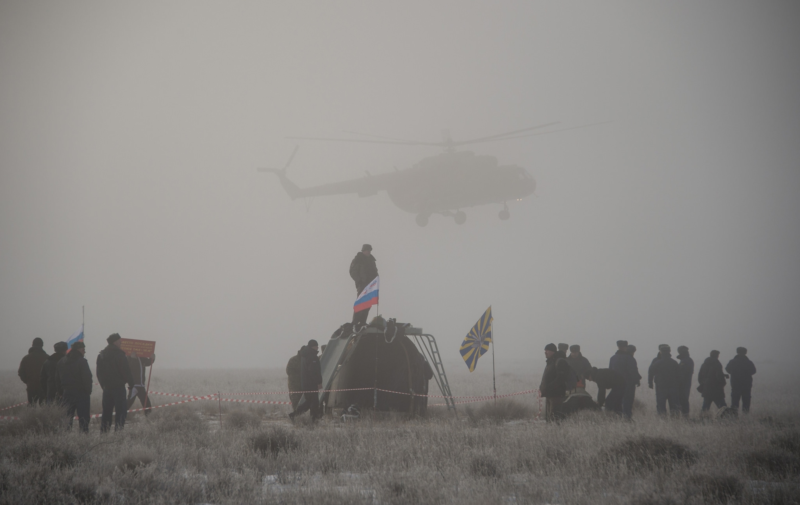 Russian support personnel work around the Soyuz TMA-14M spacecraft after it landed