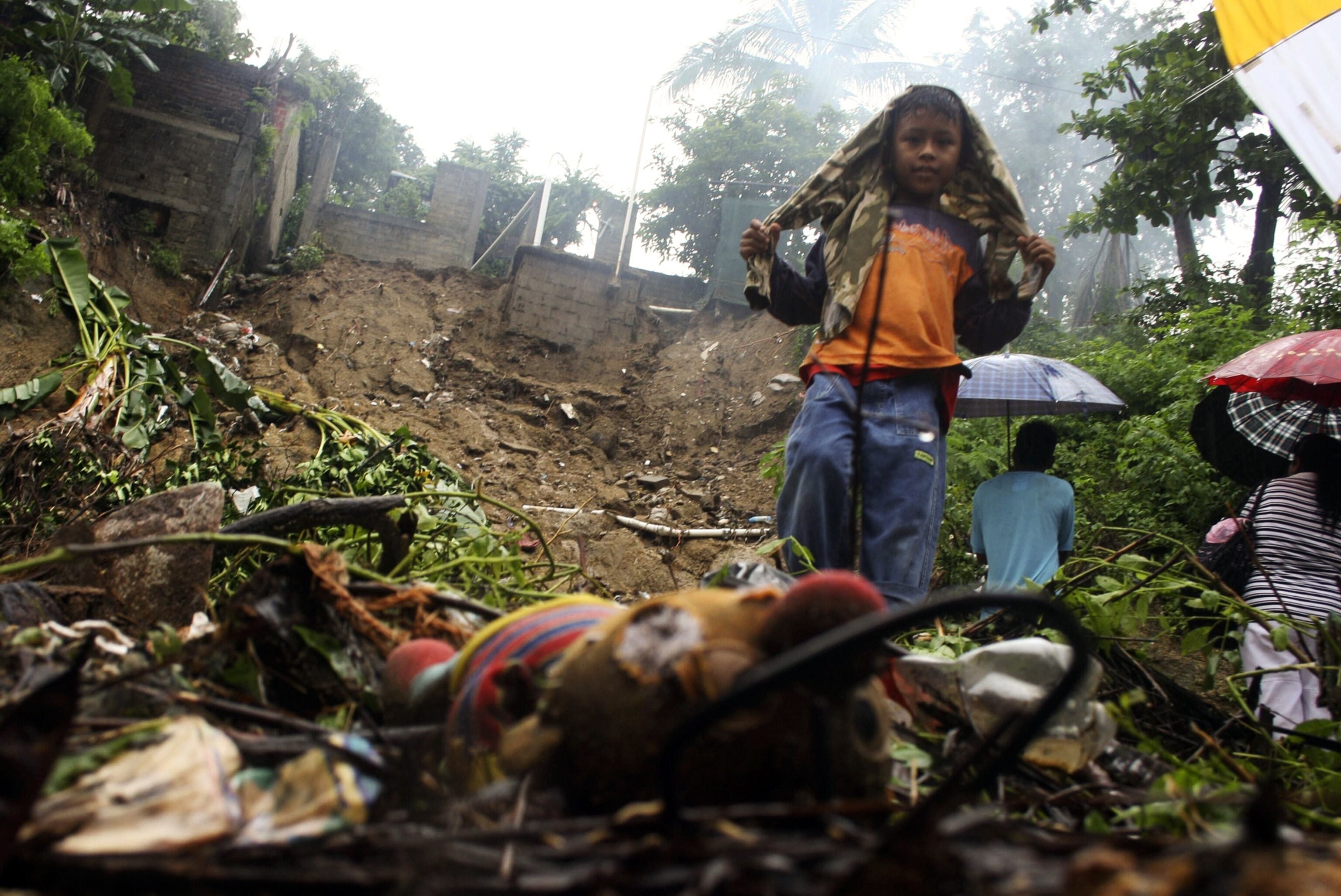 a boy standing amongst the ruins of a house destroyed by a landslide in Acapulco