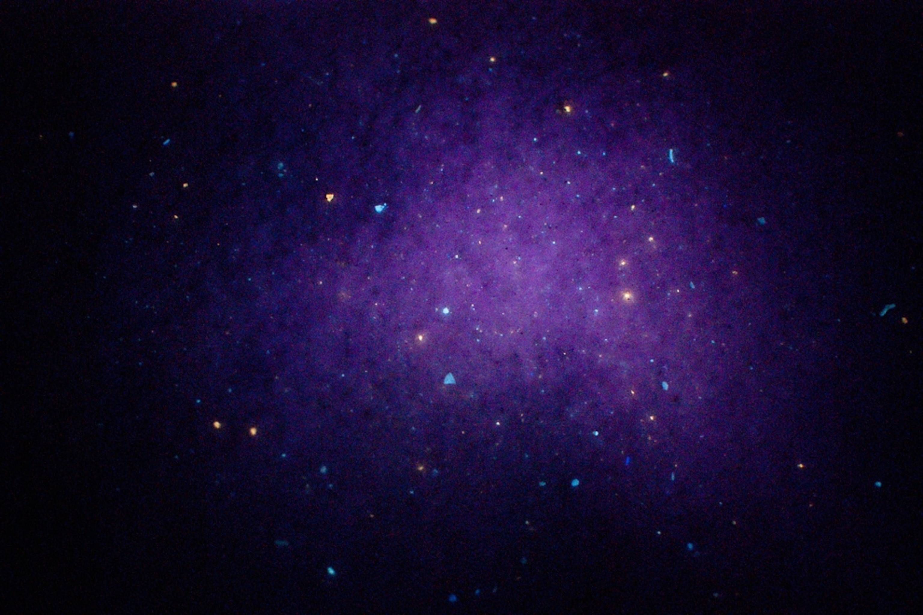 Picture of a stretch of beach sand with flecks of oil from the Gulf spill glowing under UV light.