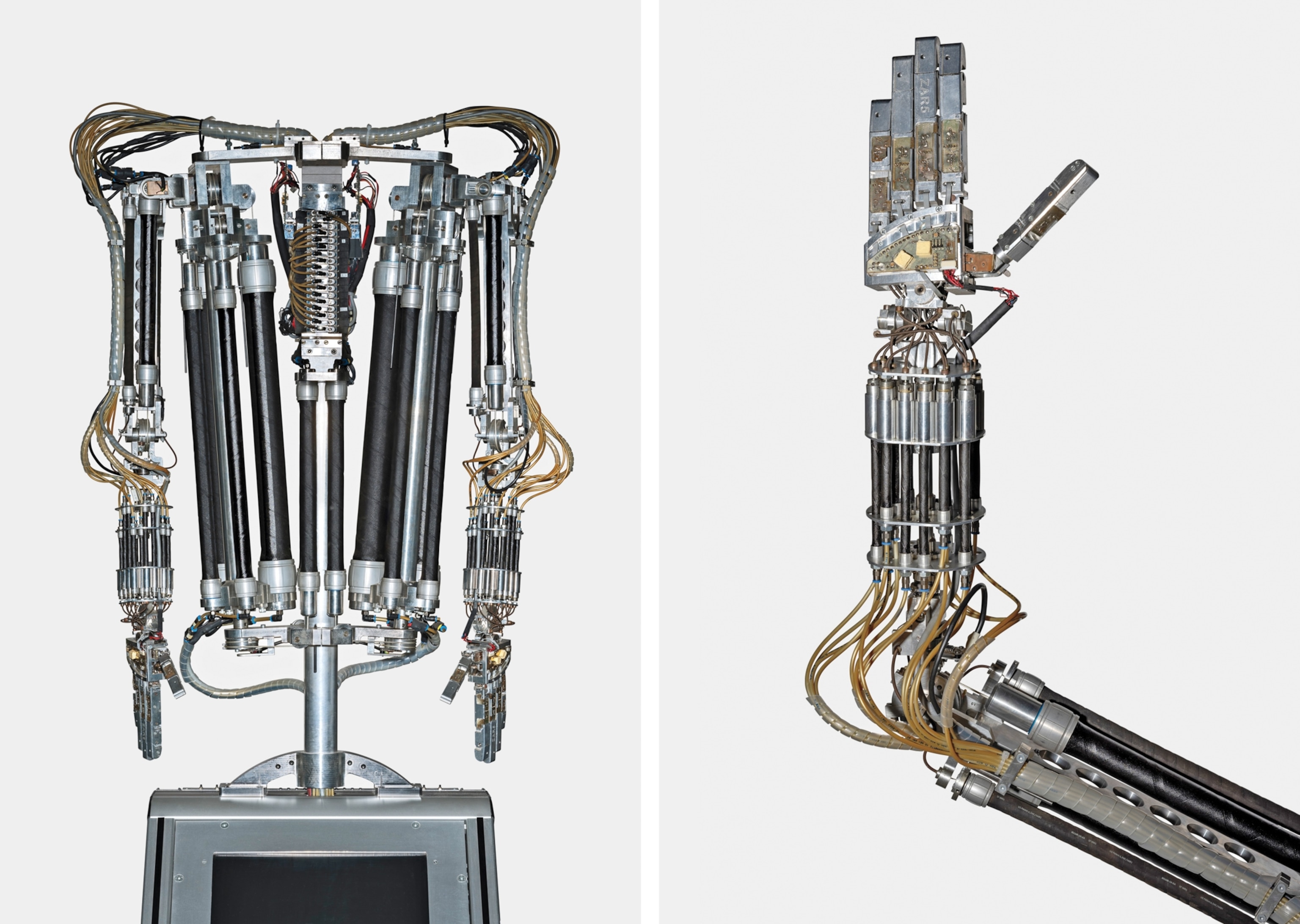 Humanoid robots. On the left, a complex robot torso with two arms and numerous exposed pistons and wires against a plain background. On the right, a robotic arm with intricate metal and wire components. The mechanical hand is open, displaying detailed joints and cables.