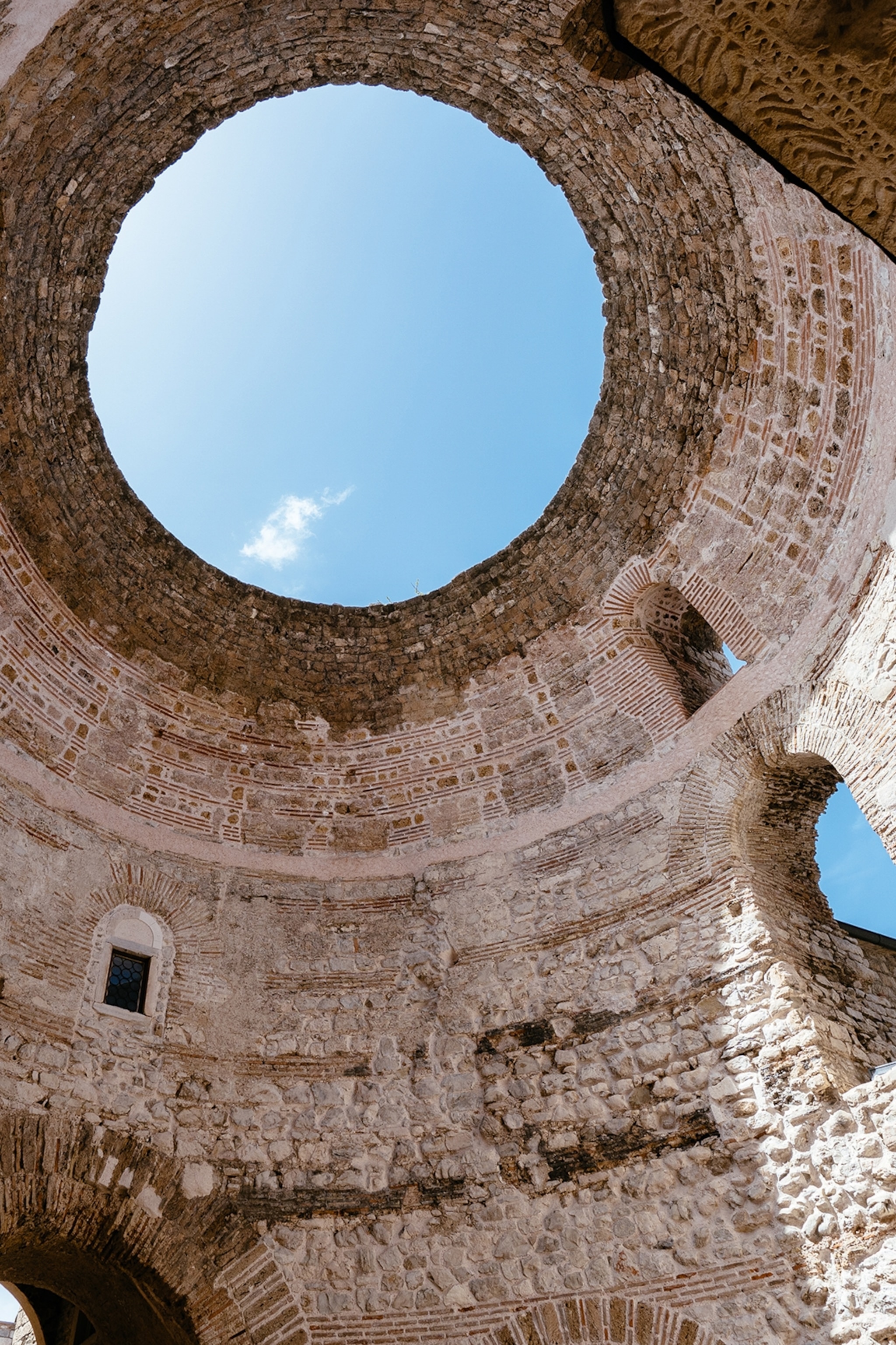 A stone vestibule shot from the inside of a palace with a clear sky covering the opening.