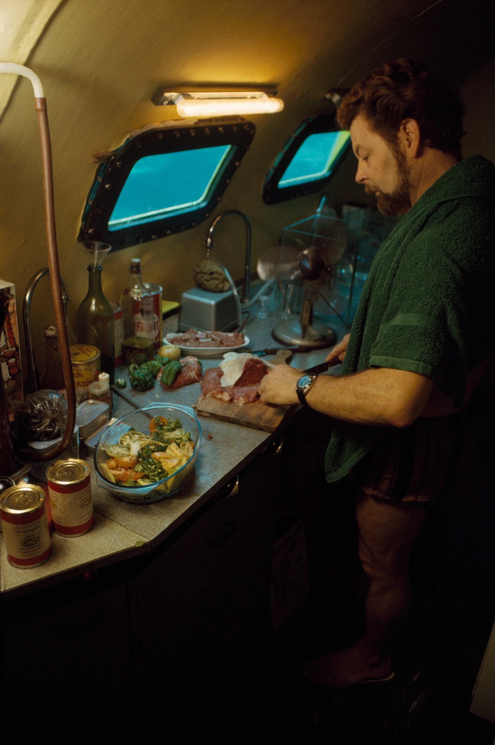 A cook in a submersible prepares red meat for the crew.