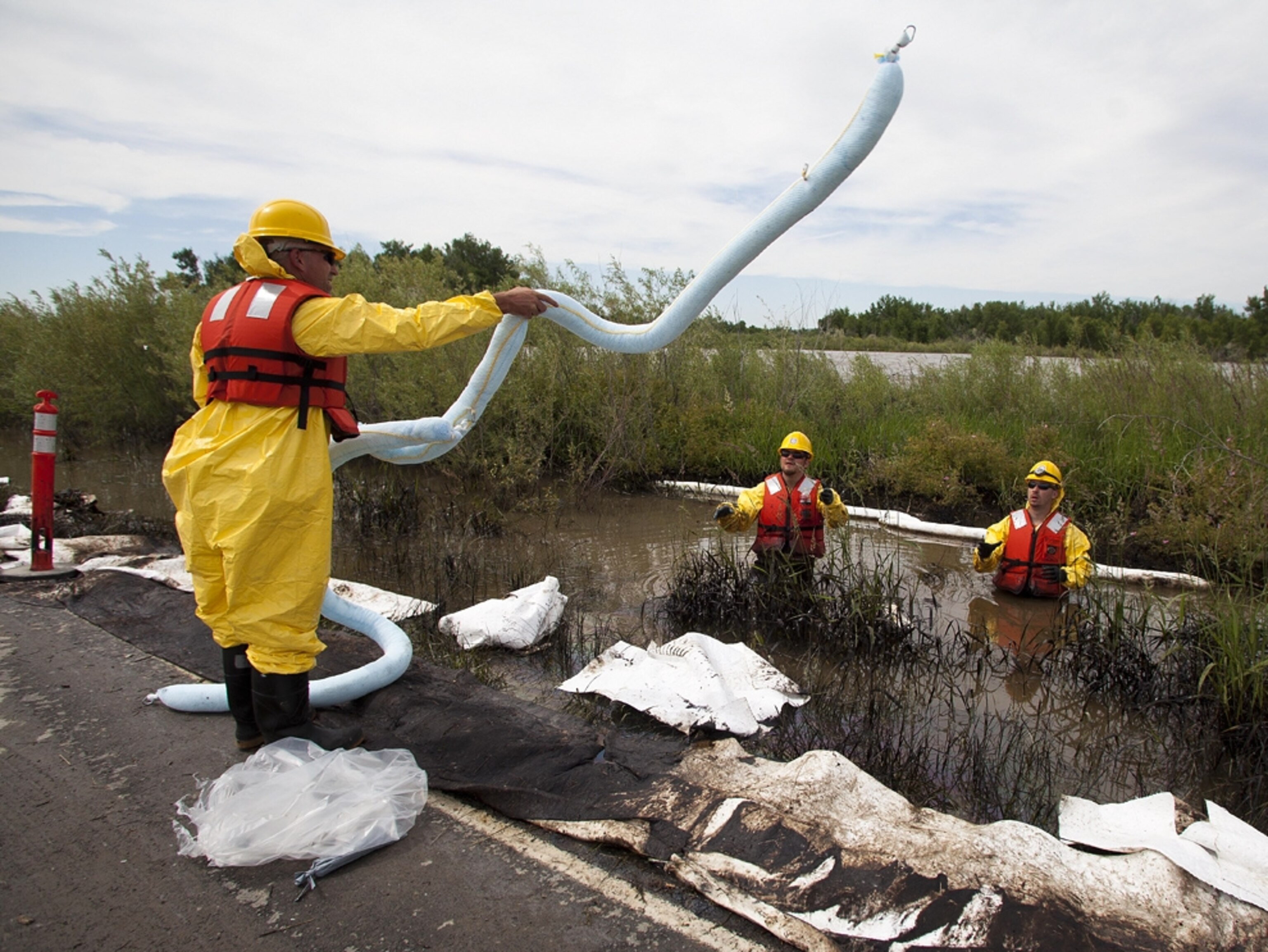 Clean up crews use an absorbent boom to collect oil from along side the Yellowstone River in Laurel, Mont., Monday July 4, 2011. An ExxonMobil pipeline near Laurel ruptured and spilled an estimated 1,000 barrels of crude into the Yellowstone. (AP Photo/Jim Urquhart)