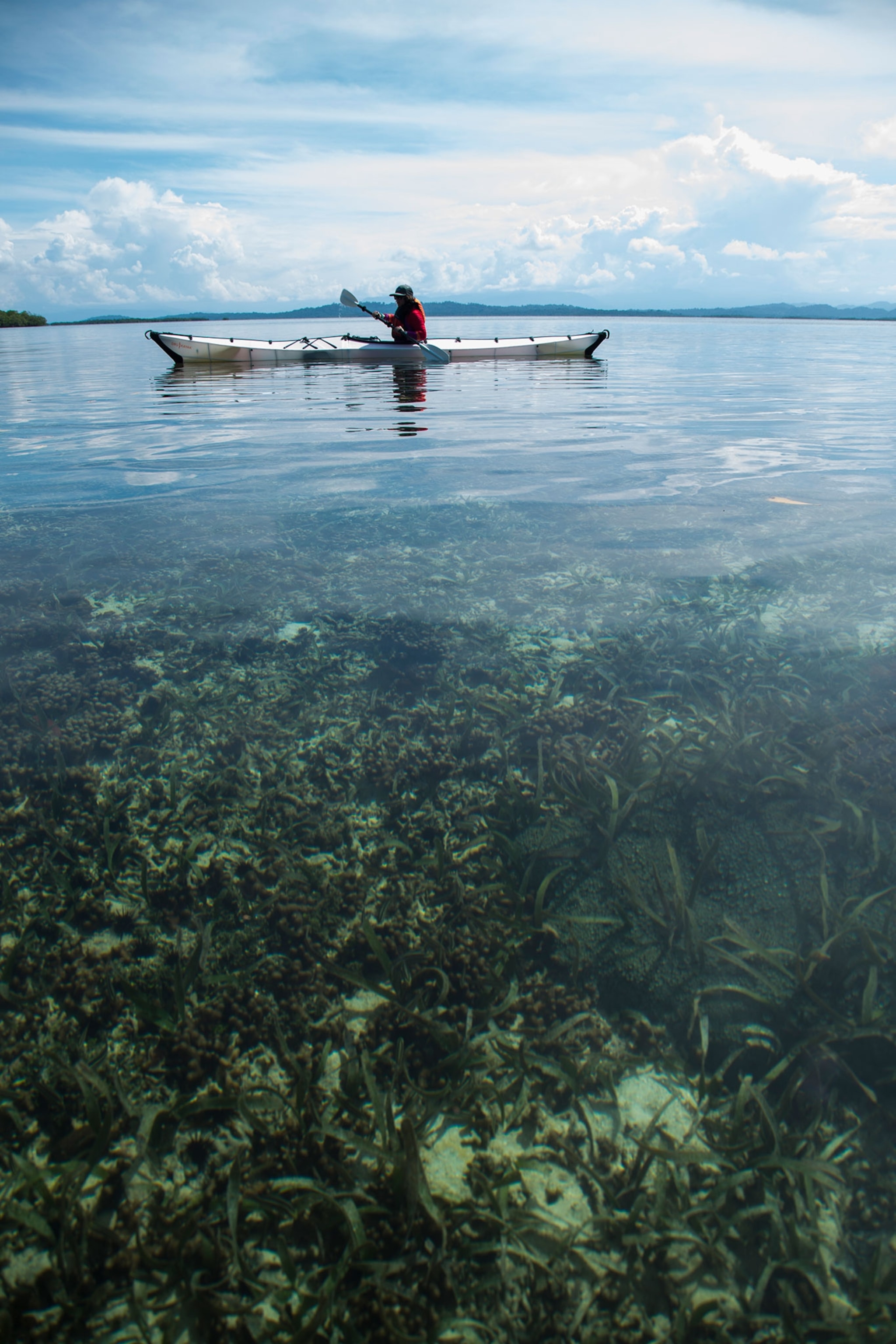 Becca Skinner paddling a kayak over sea grass in Panama