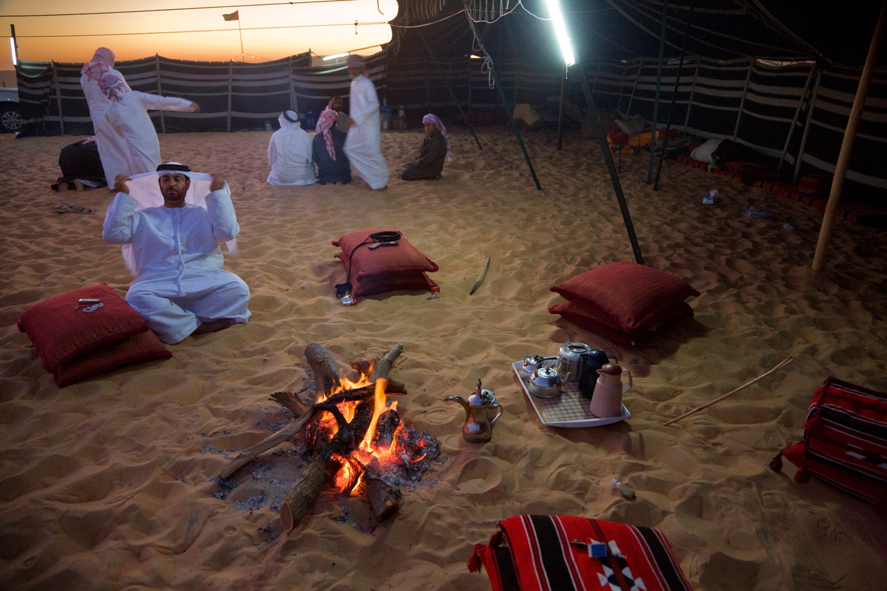 a Bedouin man sitting near a fire at a family compound