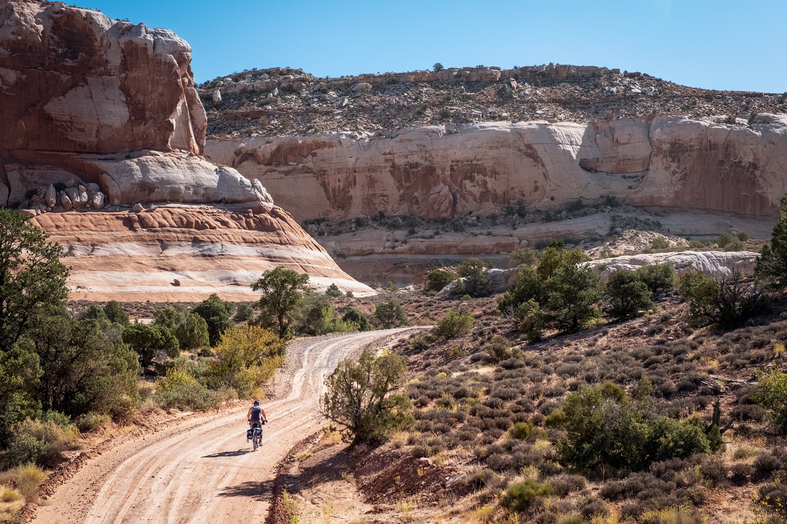 a biker on the Kokopelli trail between red sandstone cliffs in Utah