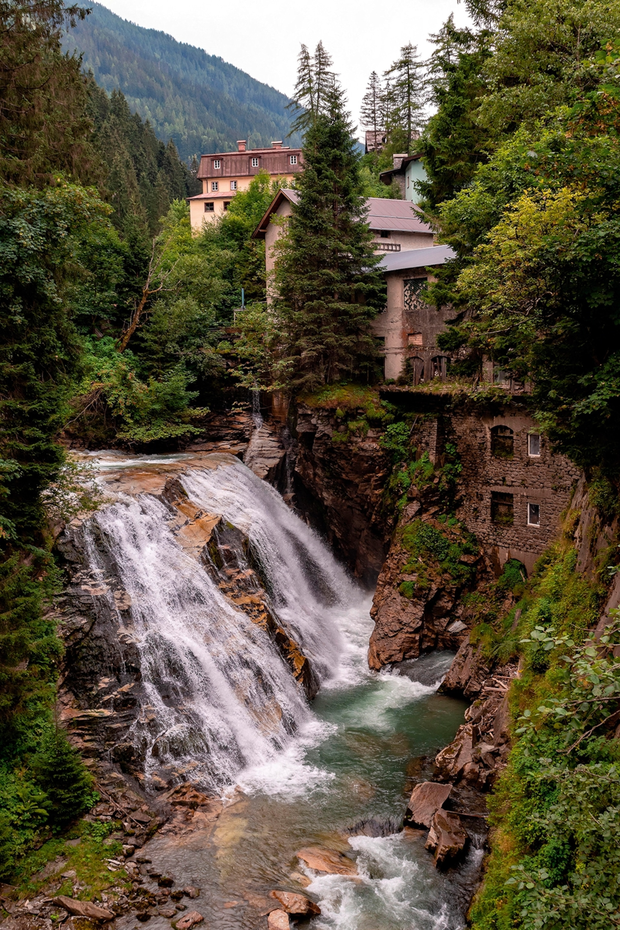 A mountain forest with a coursing water fall and a multi-level house built into the surrounding rock.