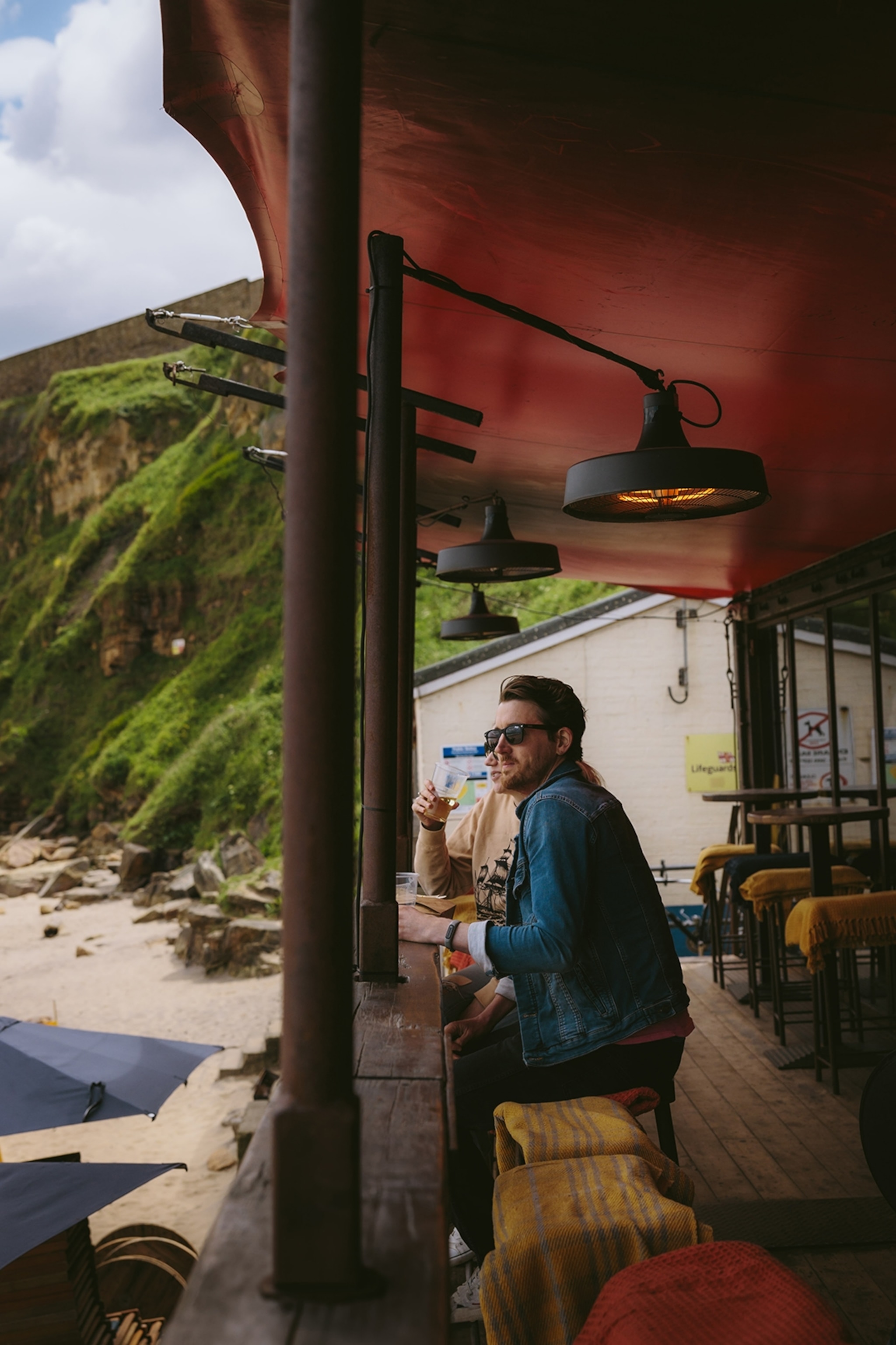 A couple sitting on a seaside wooden bar in a shack.