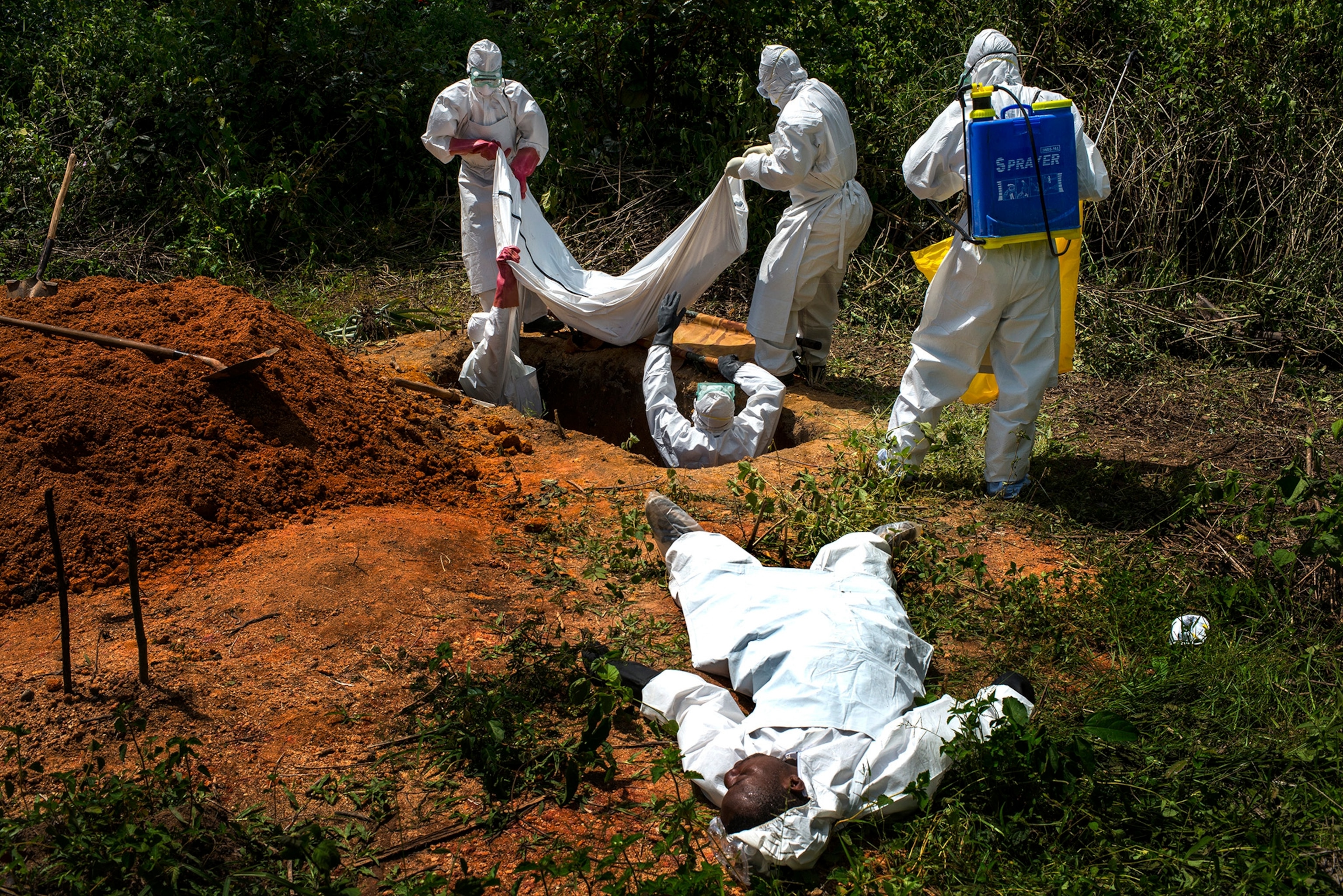 Alexander Morris lays flat on his back after he fainted due to the extreme heat inside a protective suit, while the Lofa County Health Department team buries his sister, on Friday November 7, 2014 in Voinjama,