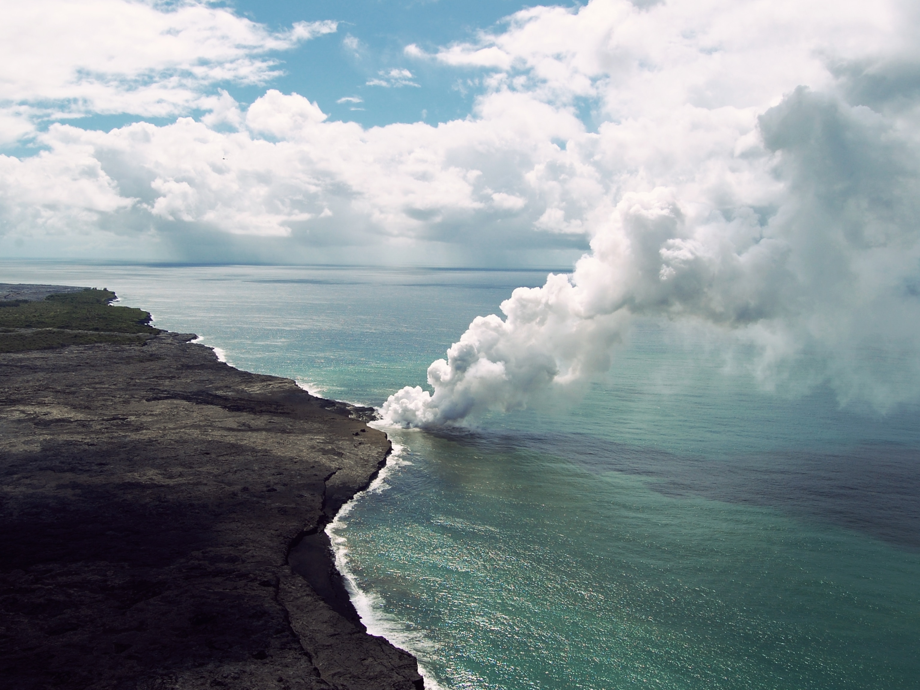 Volcano eruption picture -- aerial view of smoke rising on Hawaii coast