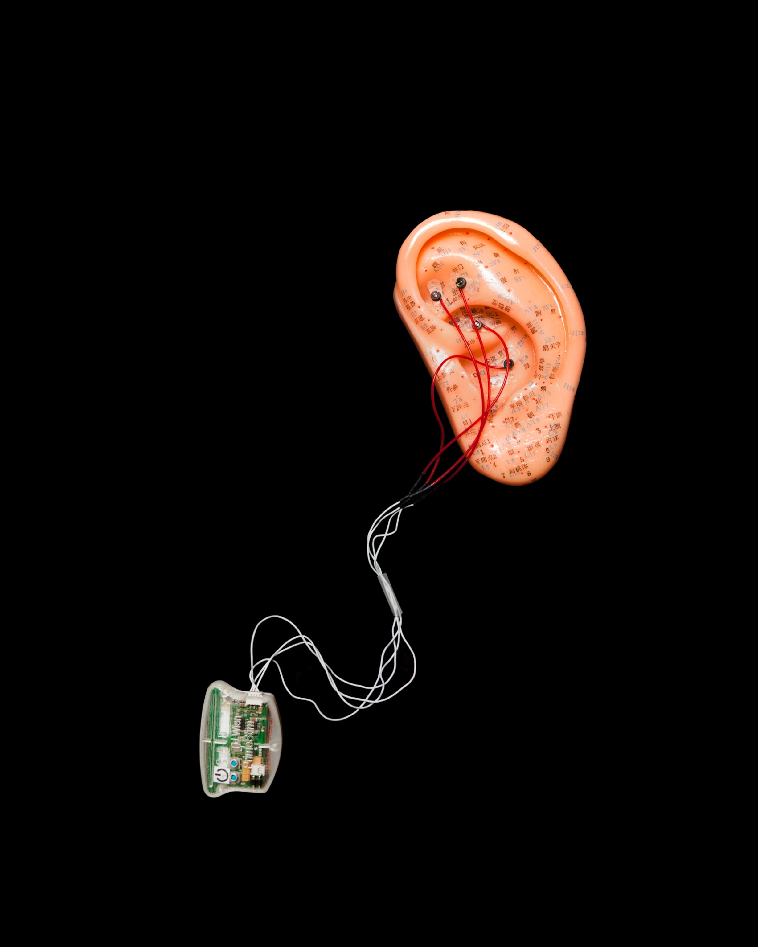 Tiny electrodes wired to a model of an ear, connected to a small control box.