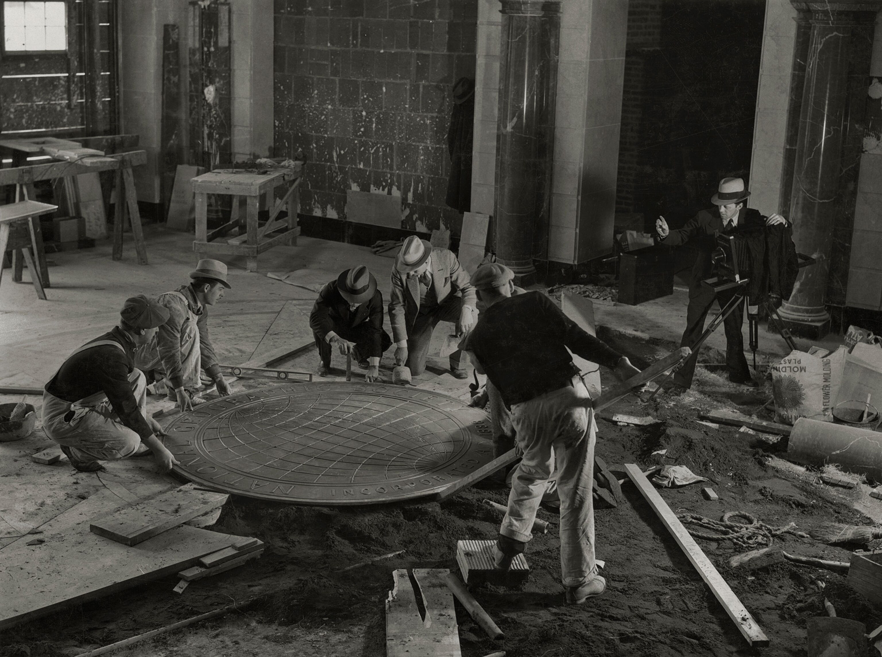 men laying National Geographic seal in floor