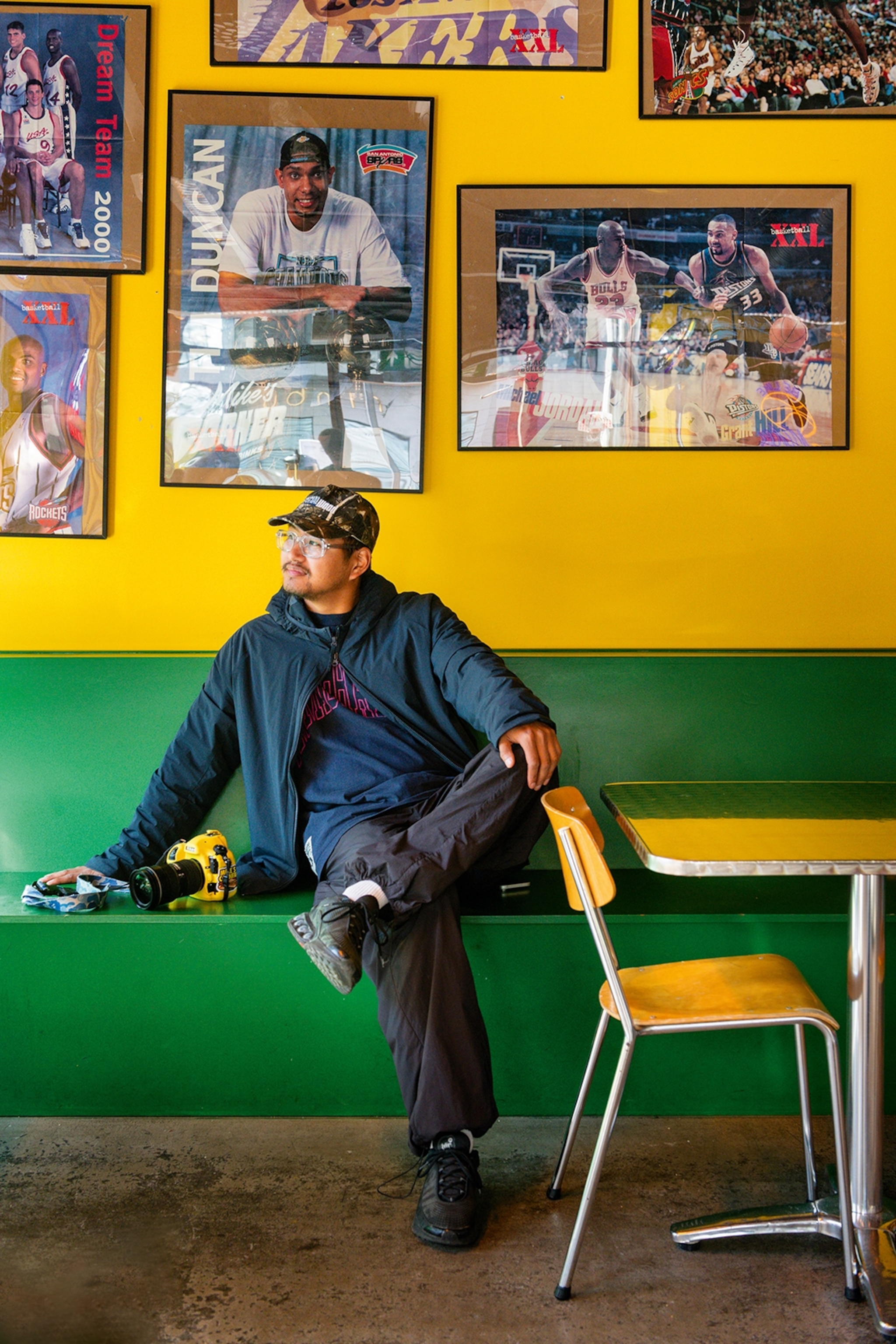 A man sits on a bench in a brightly coloured restaurant.