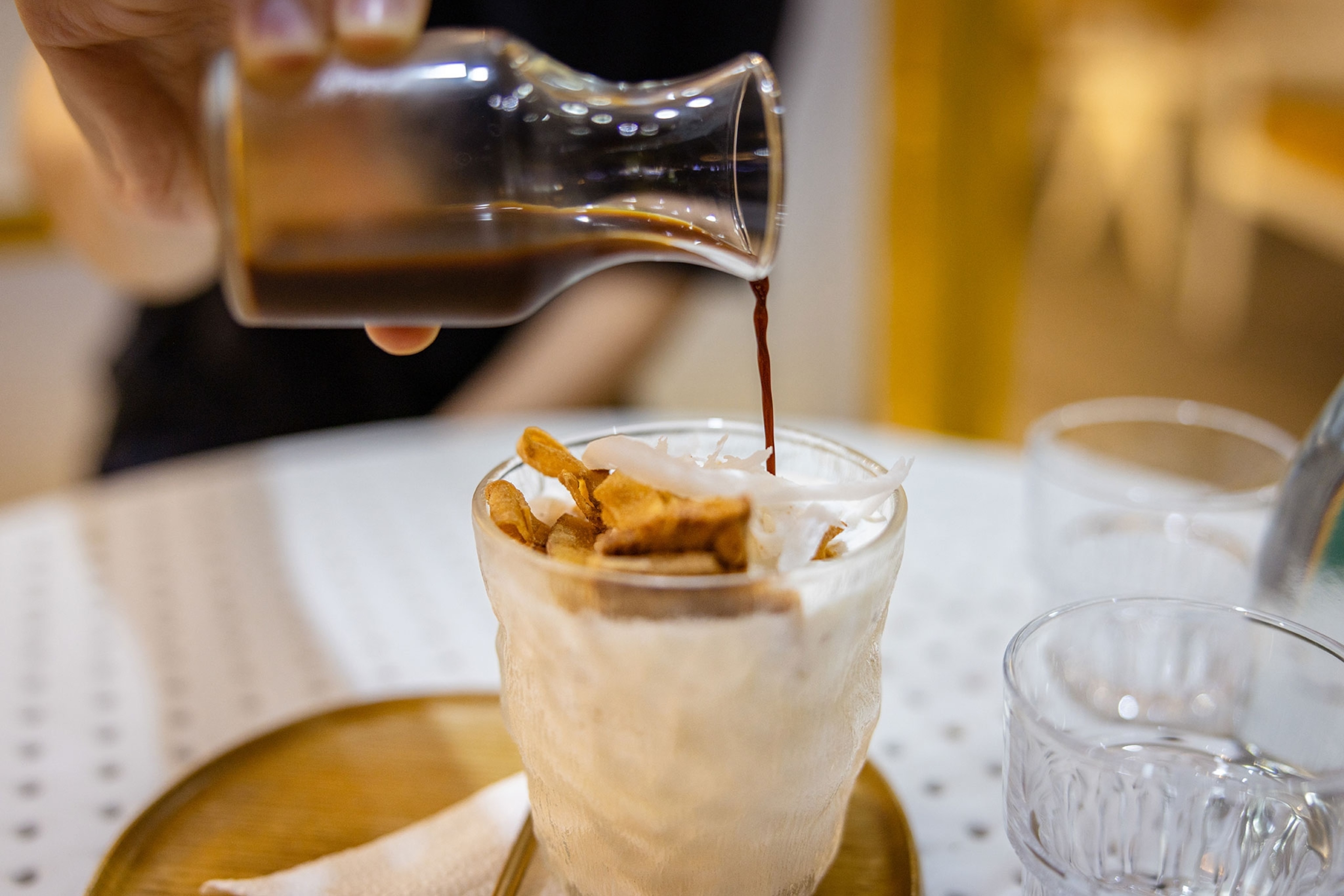 Young lady is preparing coconut coffee at coffee shop.