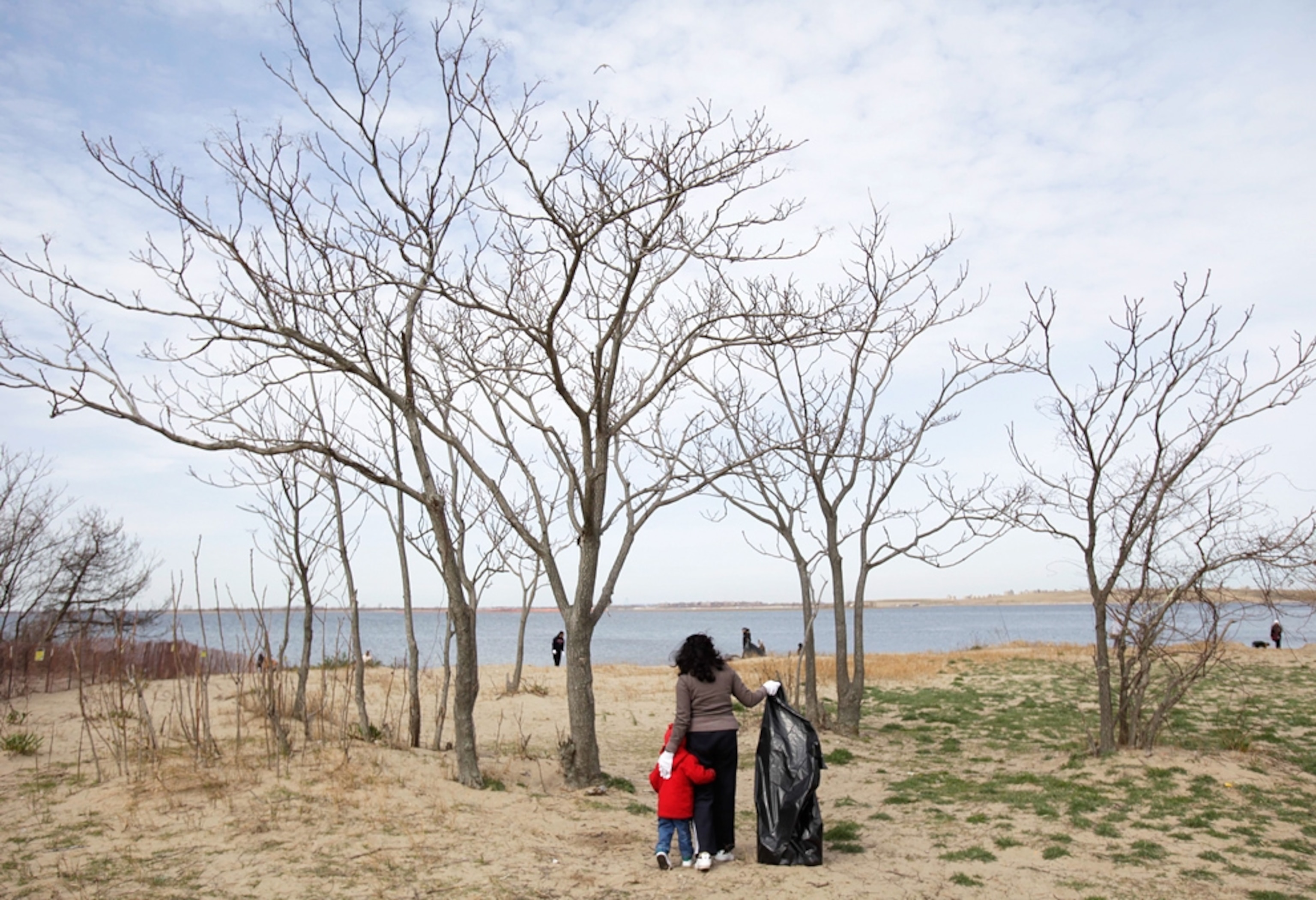 Dhanmattie Harripersaud gets help from her son Gurudeo, 2, during a beach clean-up on Earth Day at Gateway National Recreational Area in New York, Friday, April 22, 2011. (AP Photo/Seth Wenig)