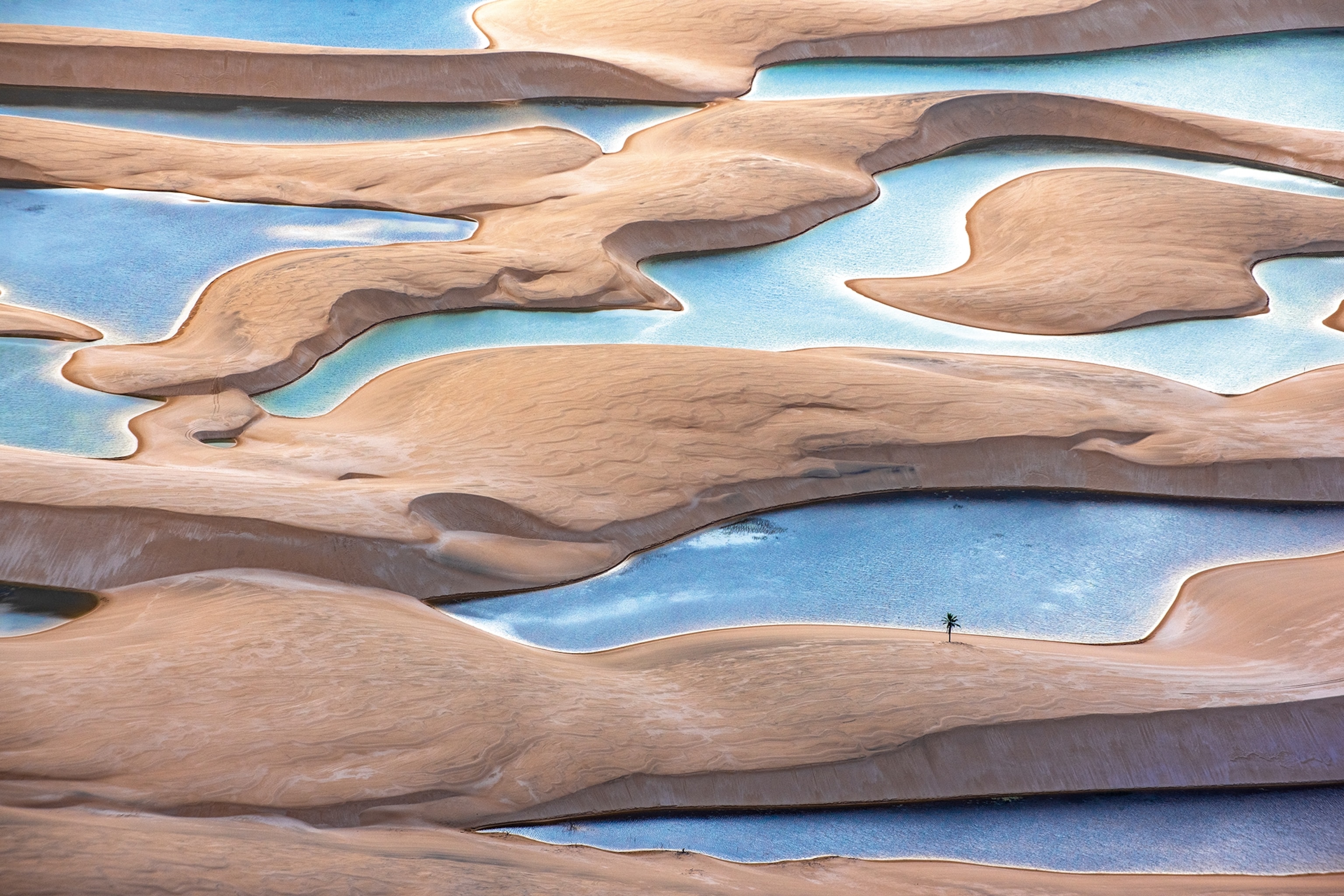 A landscape shot of an impressive sand dune with water snaking in between the sandy hills.