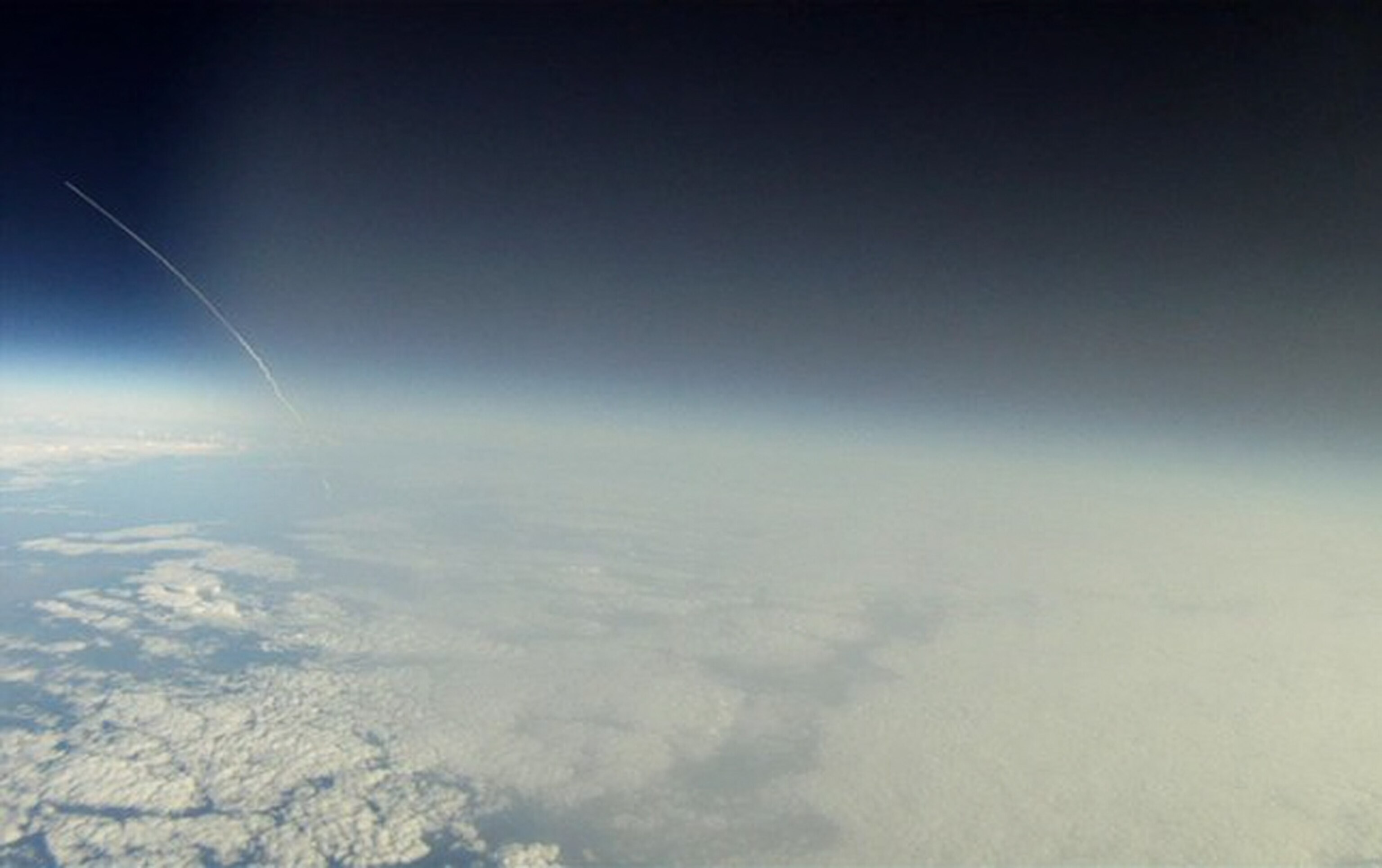 the space shuttle Discovery's exhaust plume arcing from Earth into space.