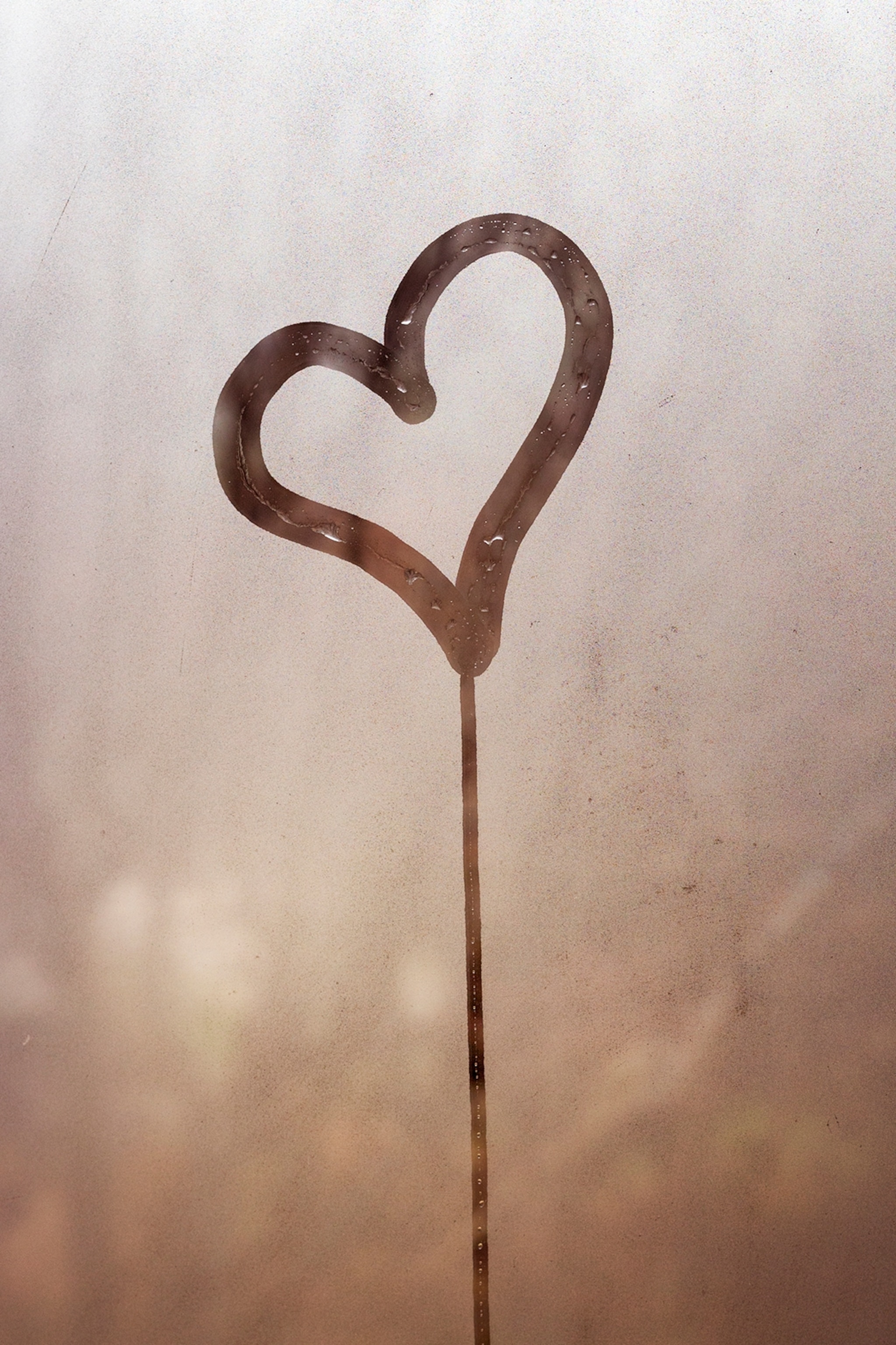 A foggy window with a heart drawn in the centre with a finger.