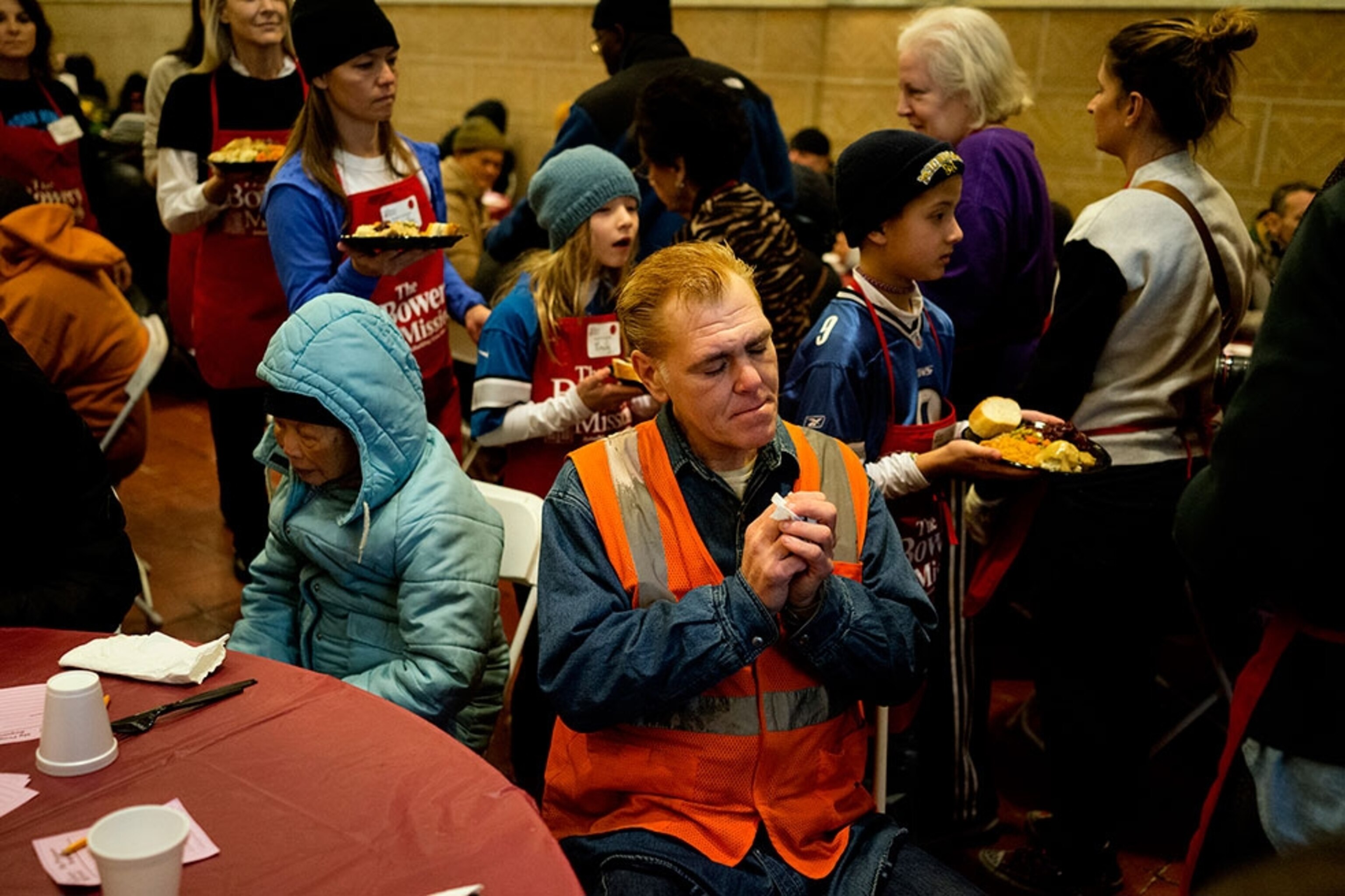 a man praying at a Thanksgiving meal at a homeless shelter