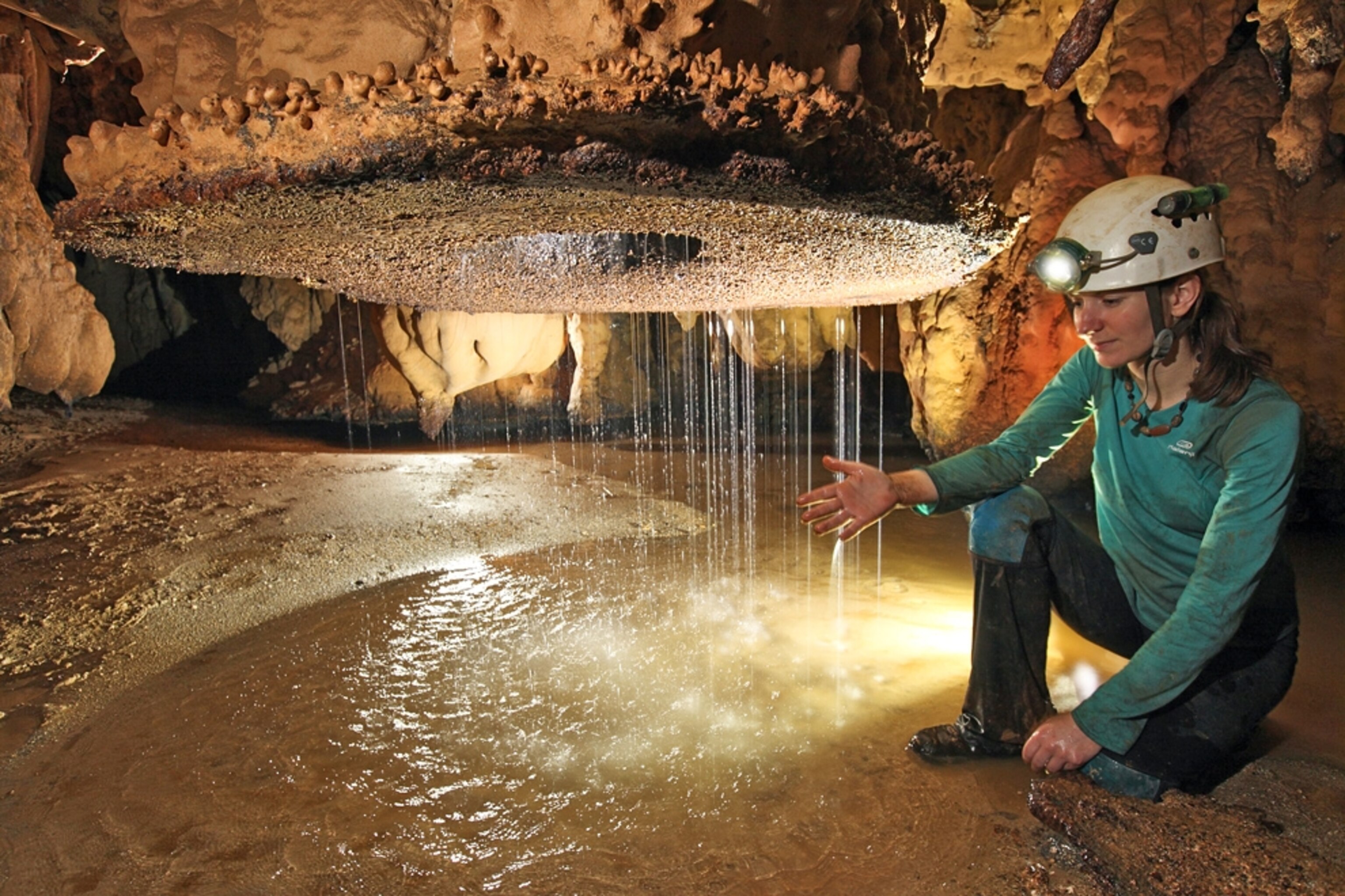 Picture of a woman examining a cave water feature in Borneo.
