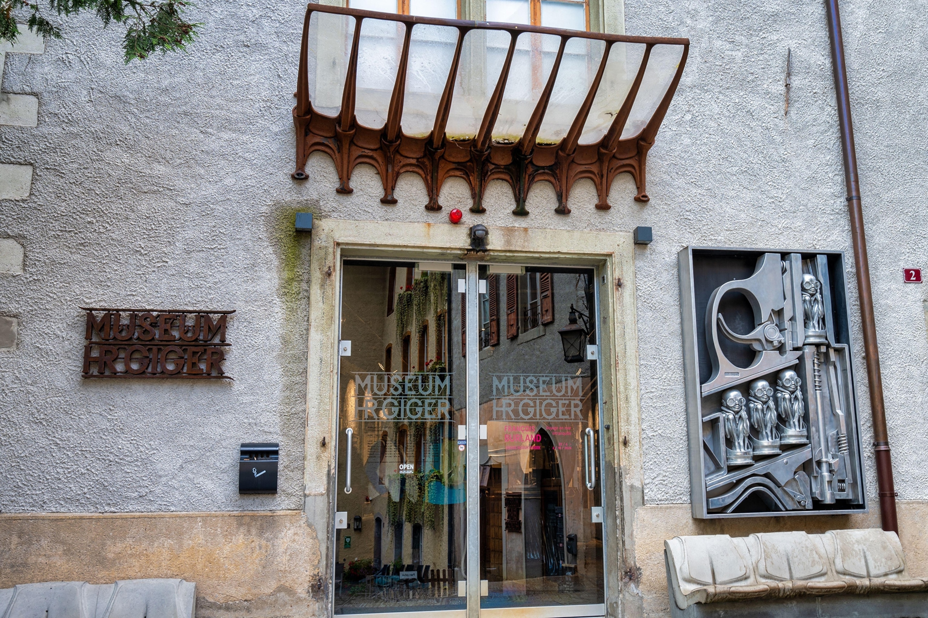 The entrance to a museum with an alien, steampunk display and a bronze roof over the doors.