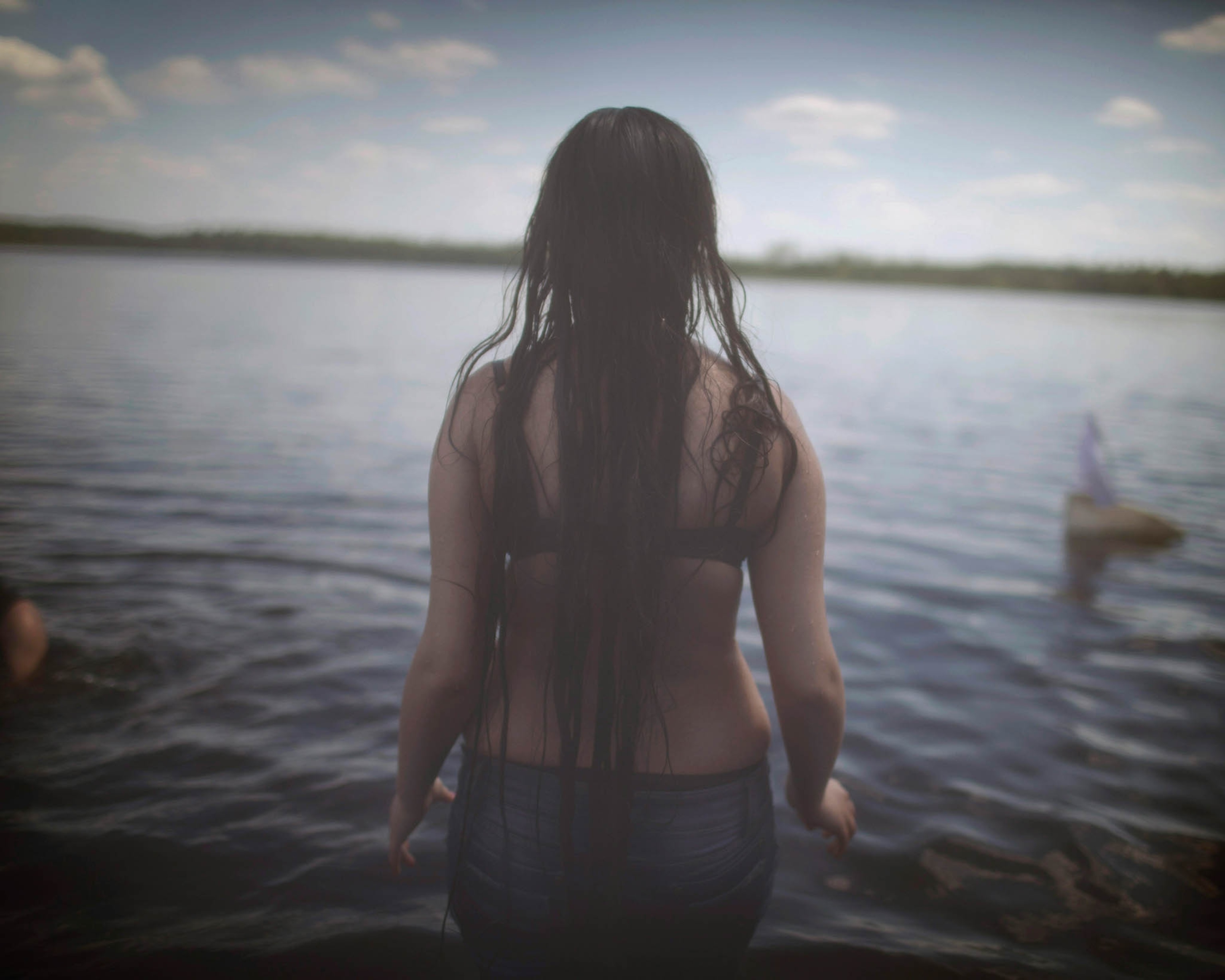 long haired girl wading into water