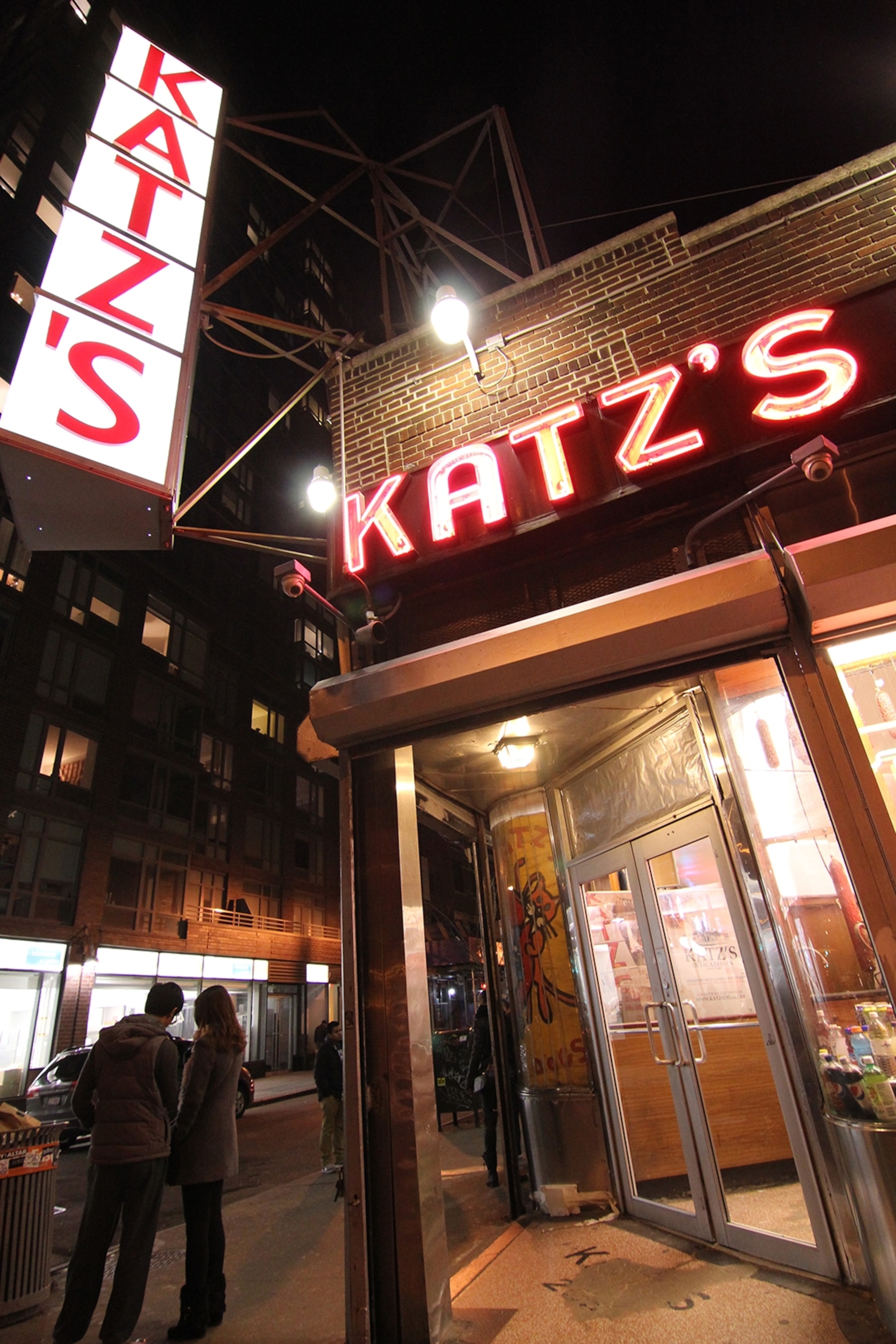 The entrance to Katz's Deli in NYC at night, with big neon lettering running along the house front and down the corner.