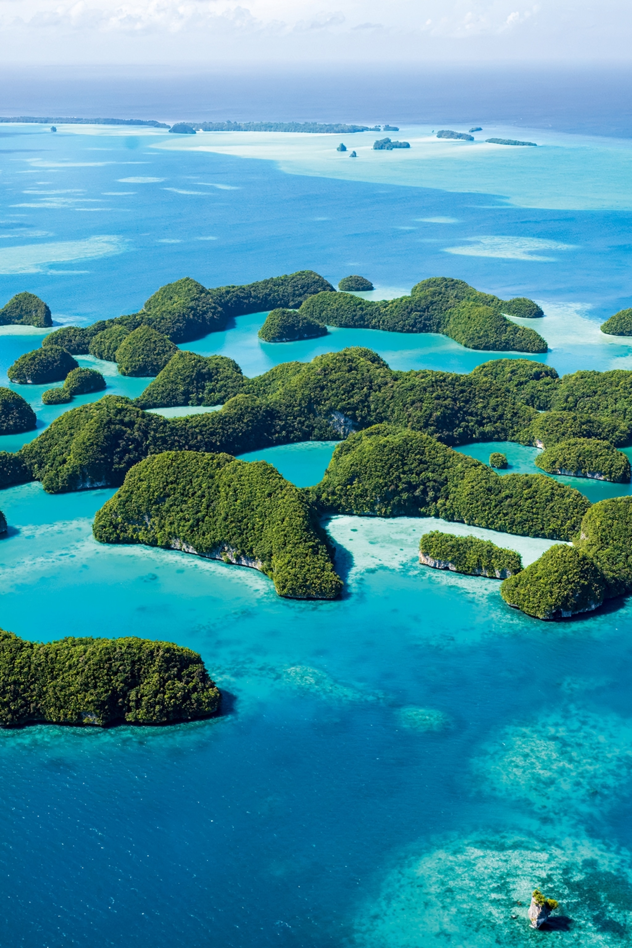 An aerial shot of an island constellation looking like moss drops in the ocean.