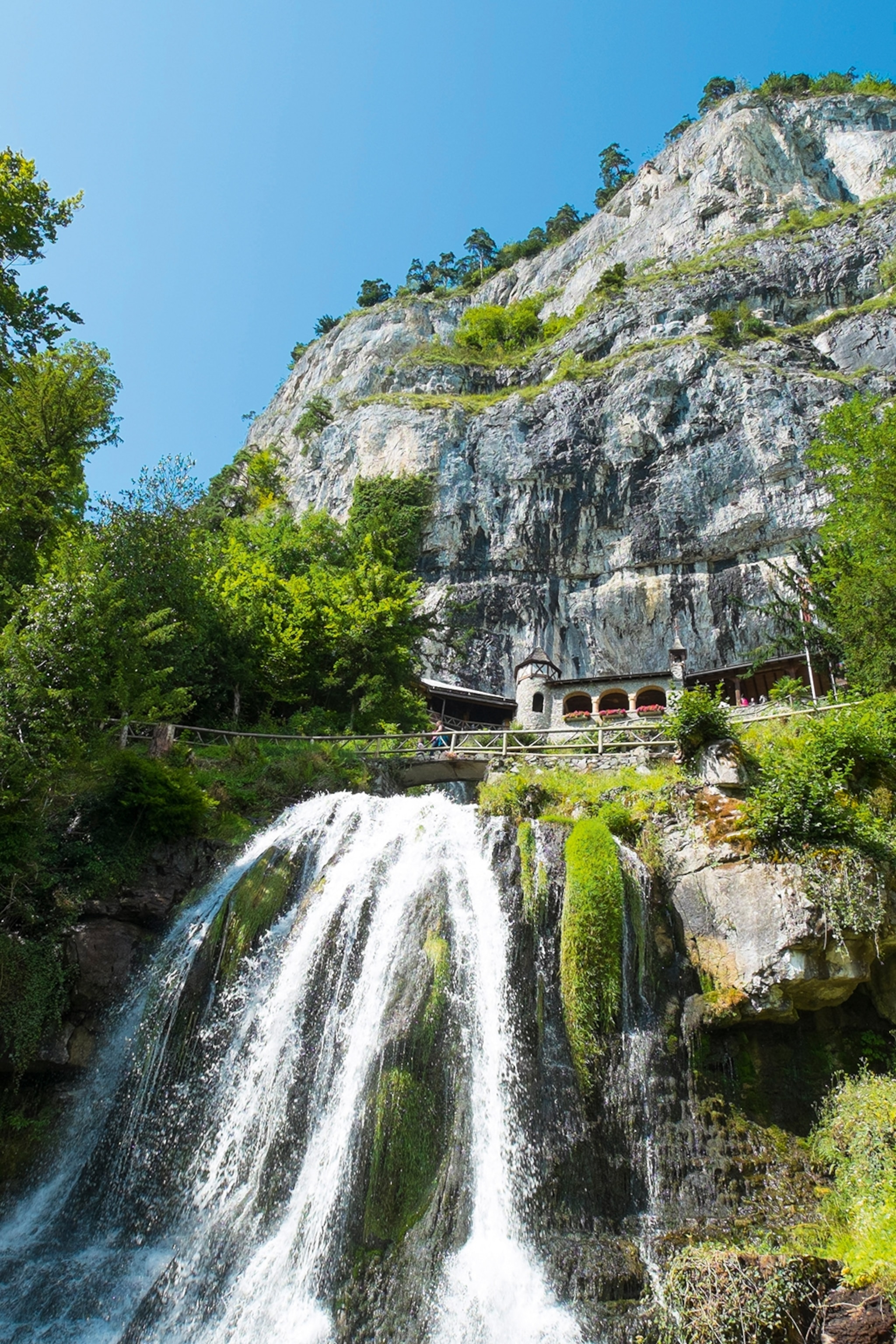 Waterfall with mountain and building behind.