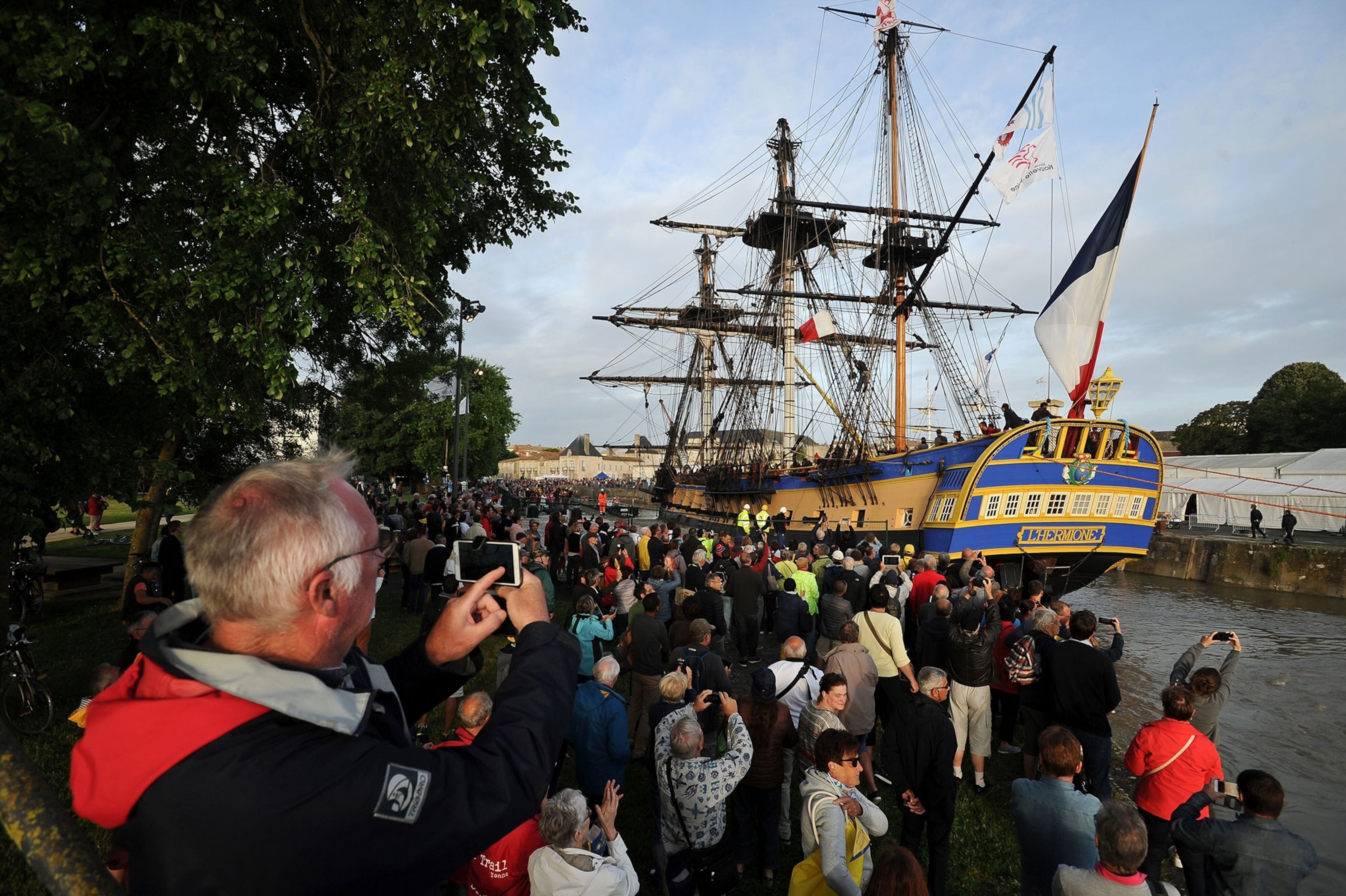 Spectators look on as the replica of the French navy frigate L'Hermione, which played a key role in the American Revolution, sails the waters of the Charente River returning to Rochefort, south-western France