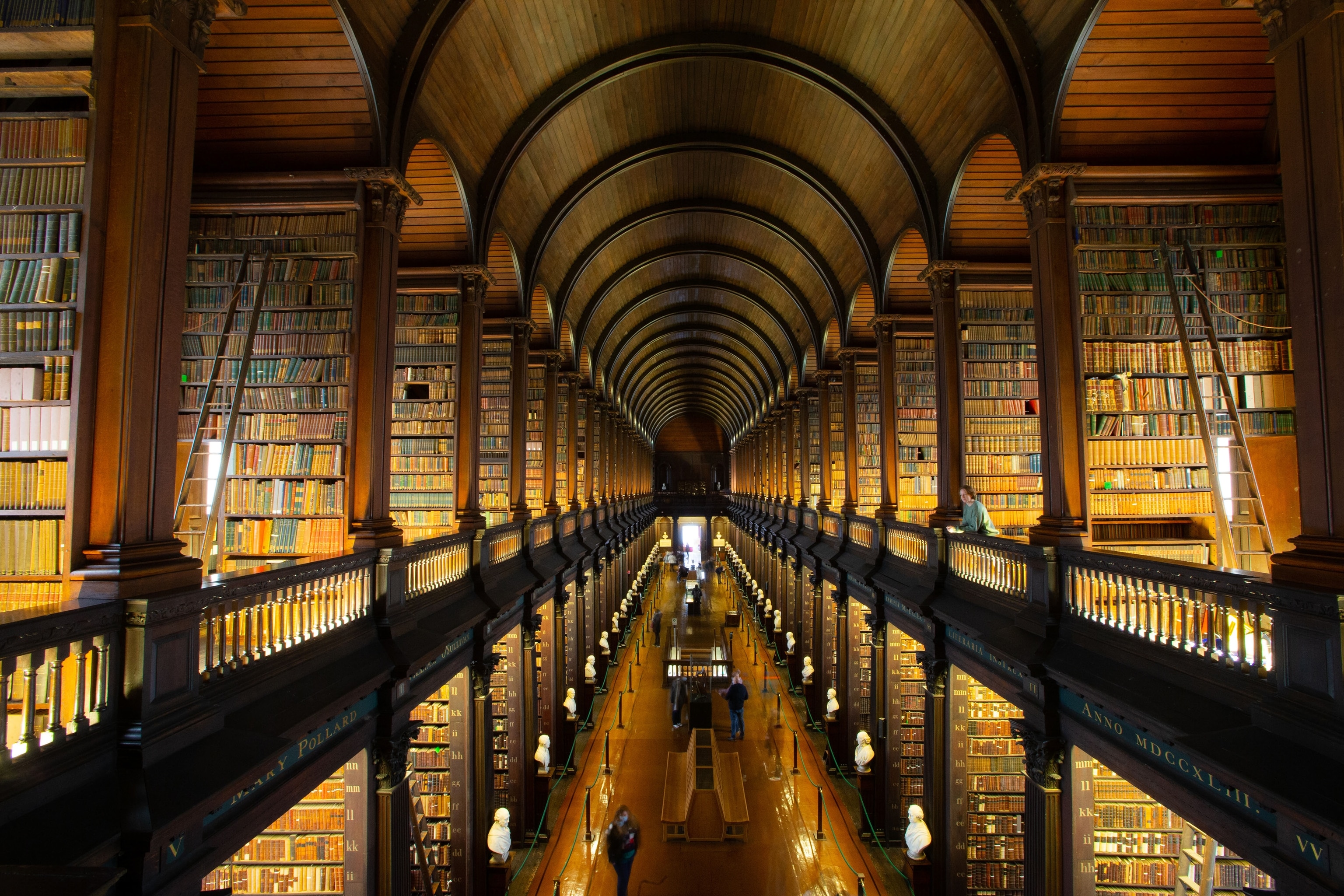 A large book room with shelves on two levels from floor to ceiling.