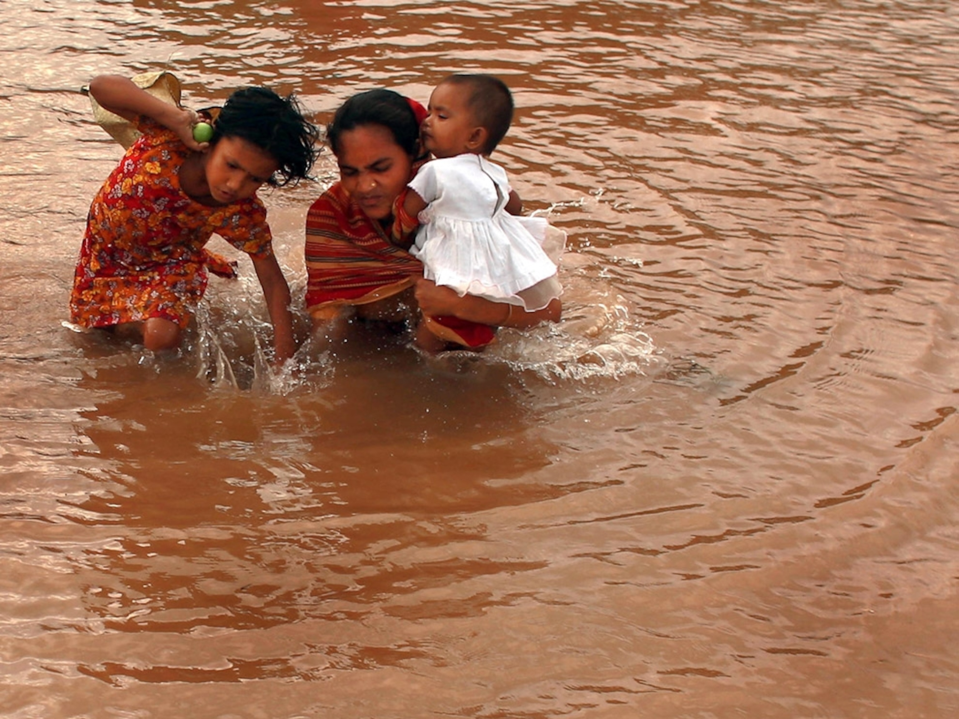 Woman and children walking through floodwaters
