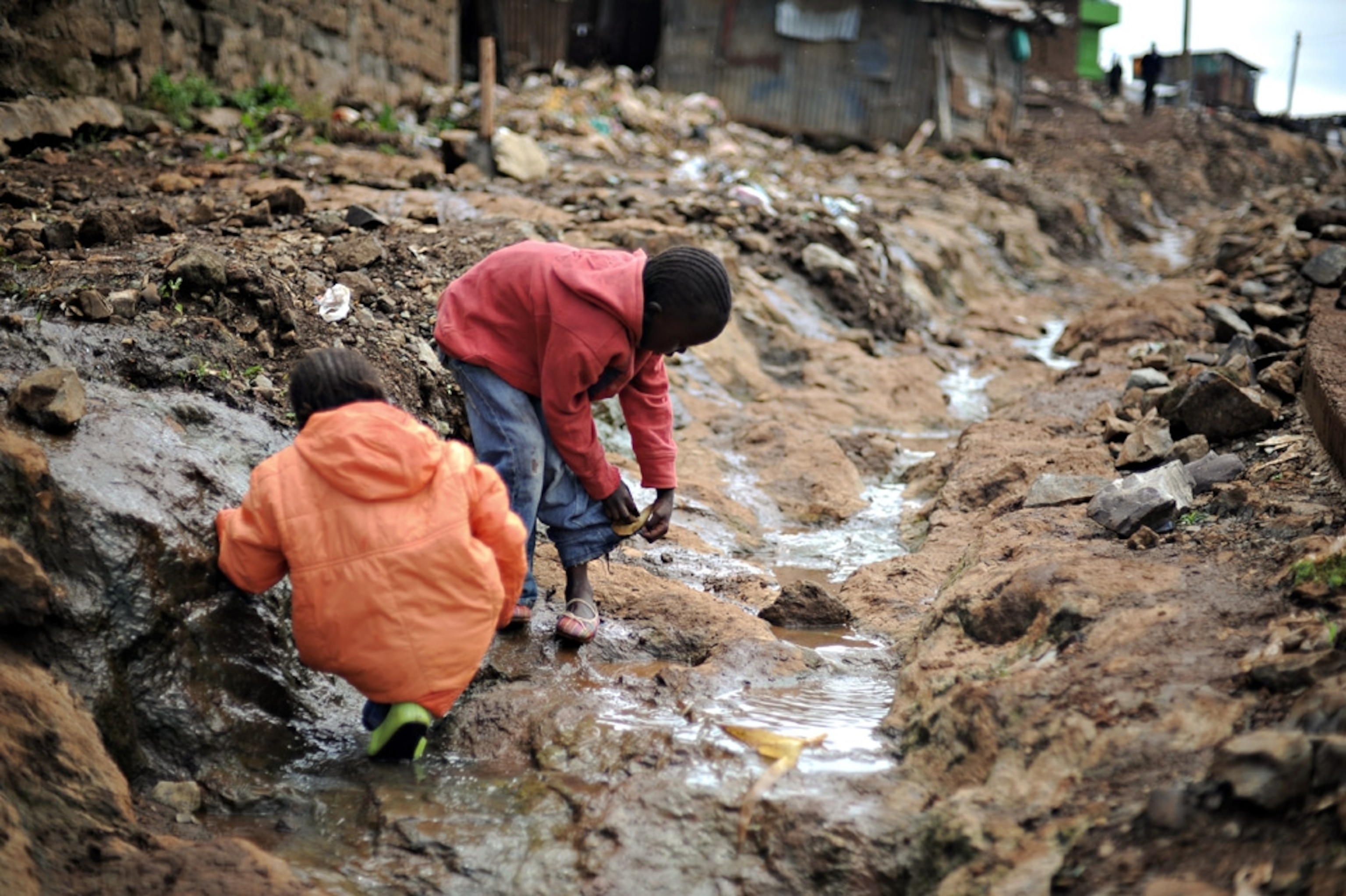 Children clean their shoes in a drainage canal in Kibera.