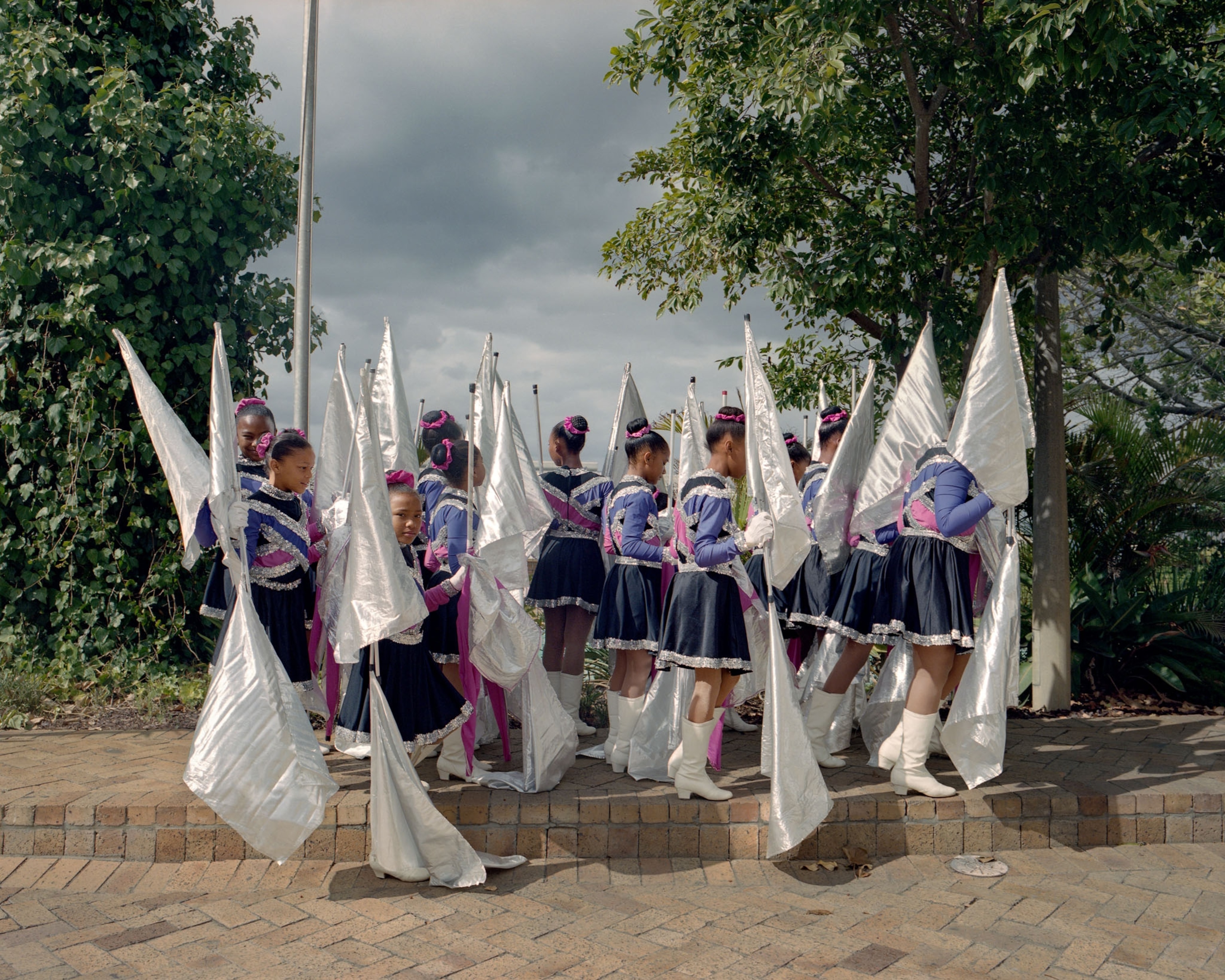young women in uniforms holding tall white flags outside