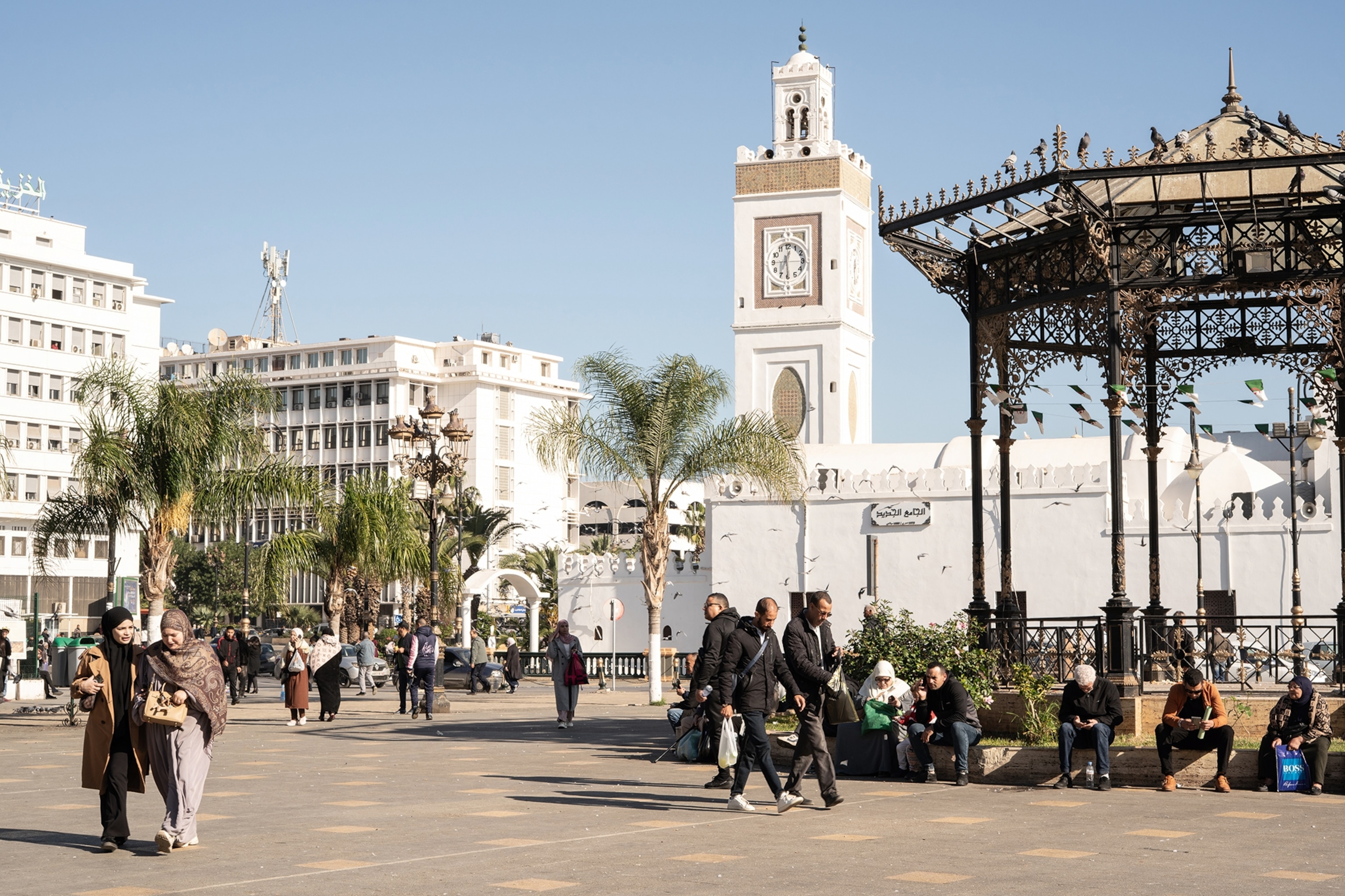 A town square with a white-stoned mosque and palm trees.