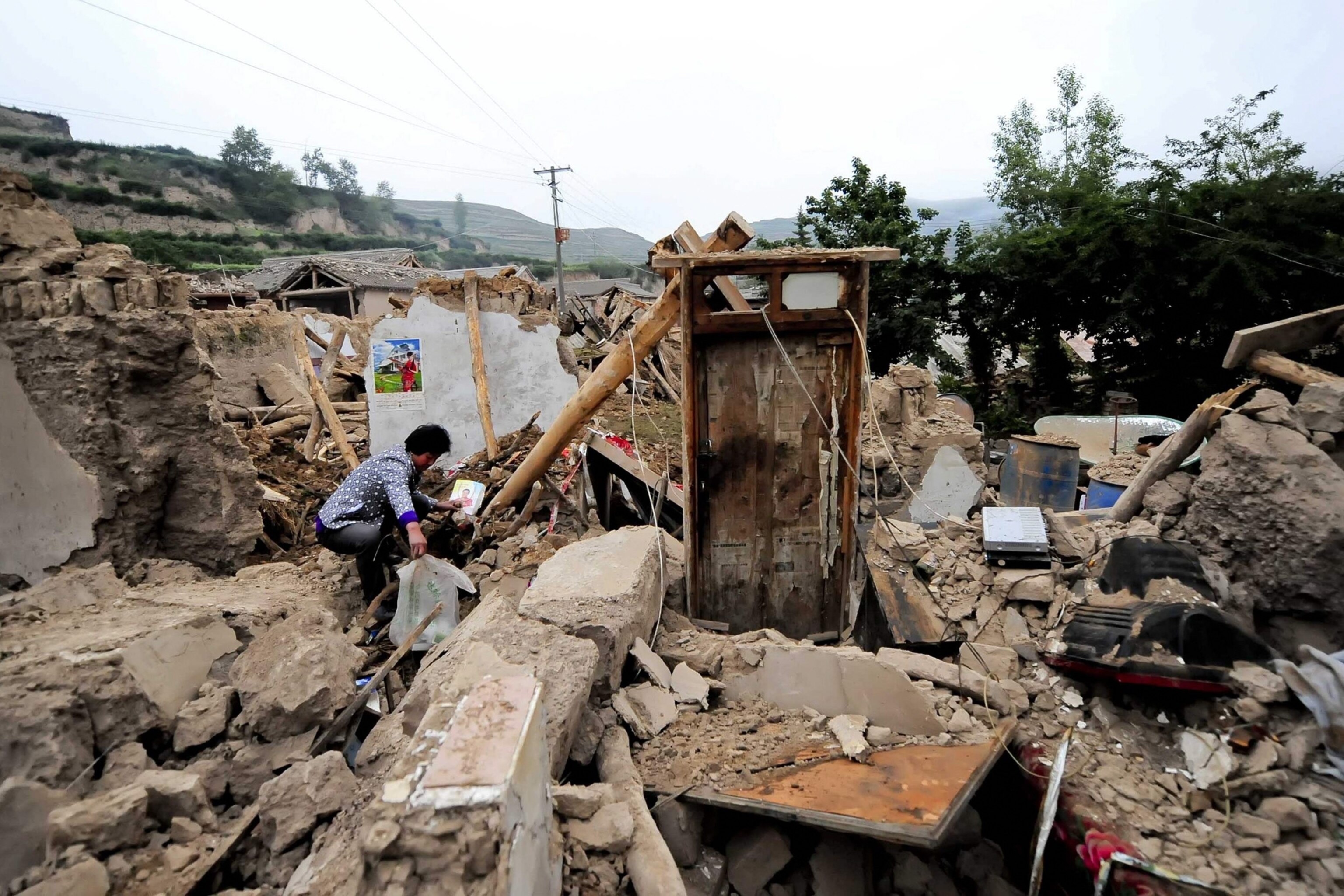 A woman is seen on ruins of a damaged house after a 6.6 magnitude earthquake hit Minxian county on Monday, Dingxi, Gansu province, July 23, 2013. The death toll from two earthquakes in China's western Gansu province has climbed to 89, with more than 500 people injured, after 1,200 buildings collapsed and tens of thousands more were badly damaged, said the official Xinhua news agency. REUTERS/China Daily (CHINA - Tags: DISASTER) CHINA OUT. NO COMMERCIAL OR EDITORIAL SALES IN CHINA