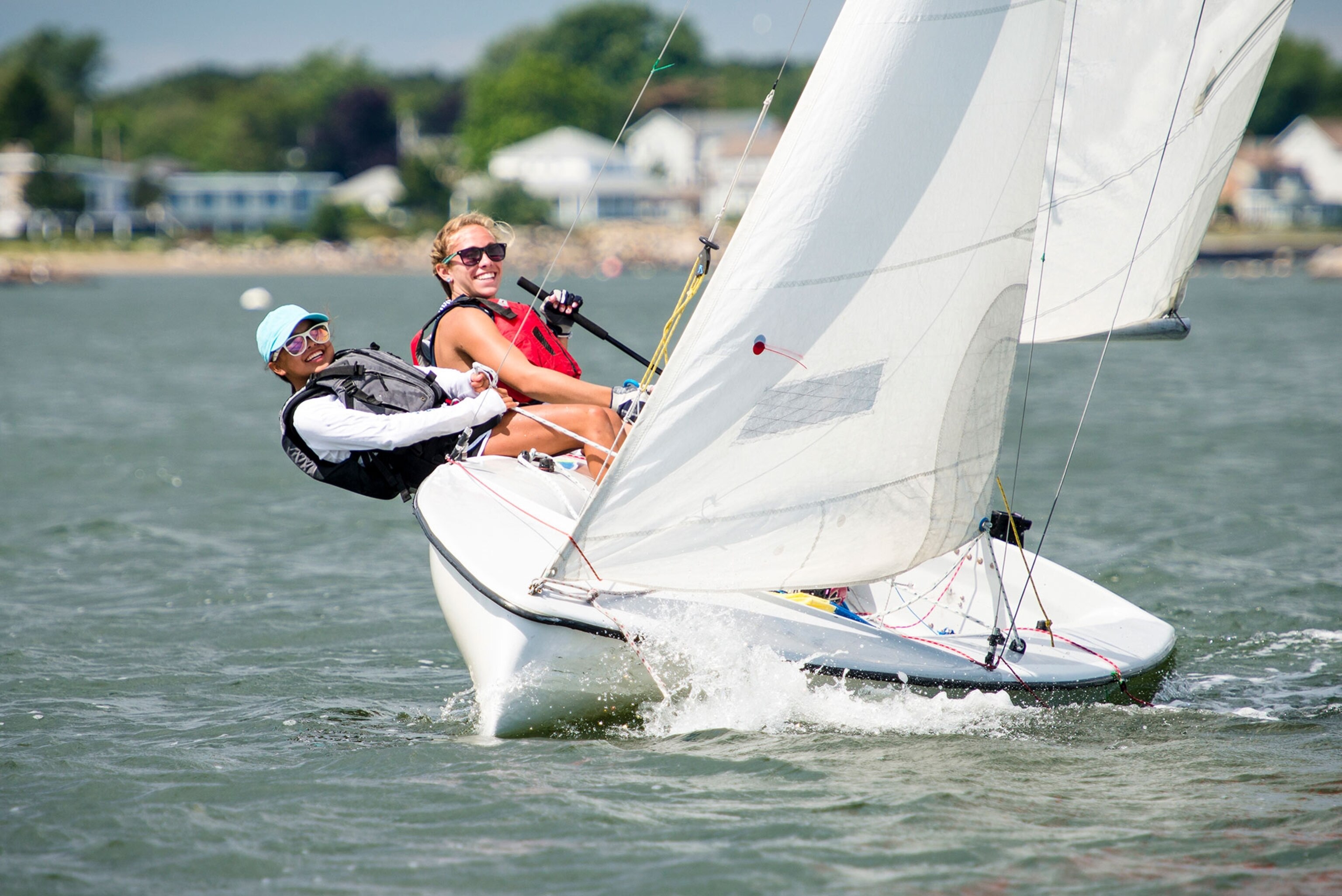 a two young sailors on a sailboat on the water in Rhode Island